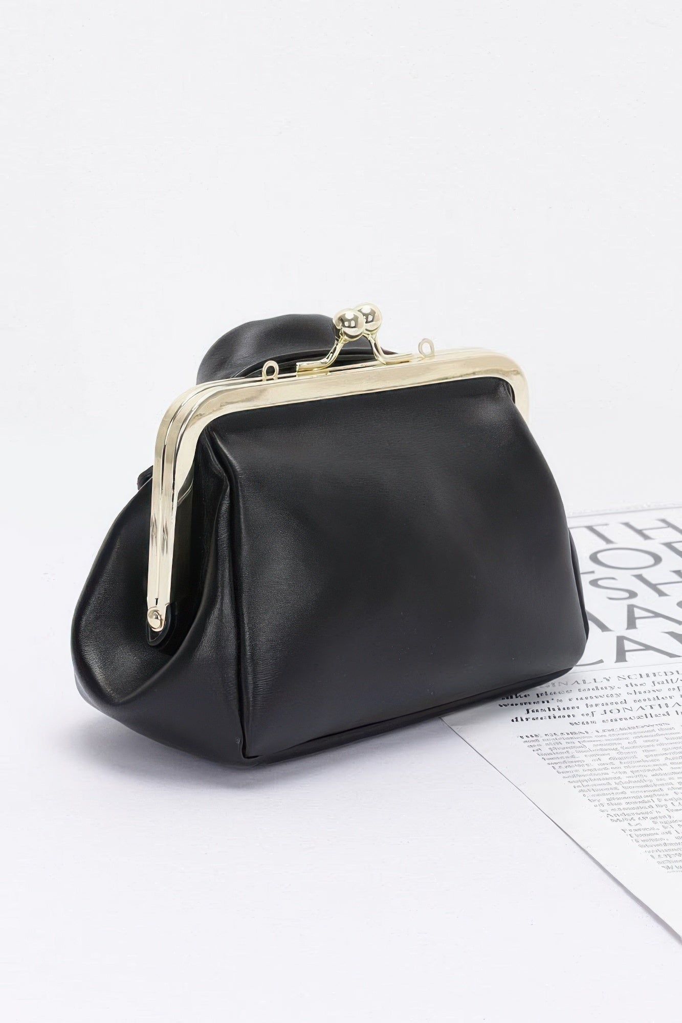 Black faux leather crossbody bag with curved clasp frame and gold-tone chain handle