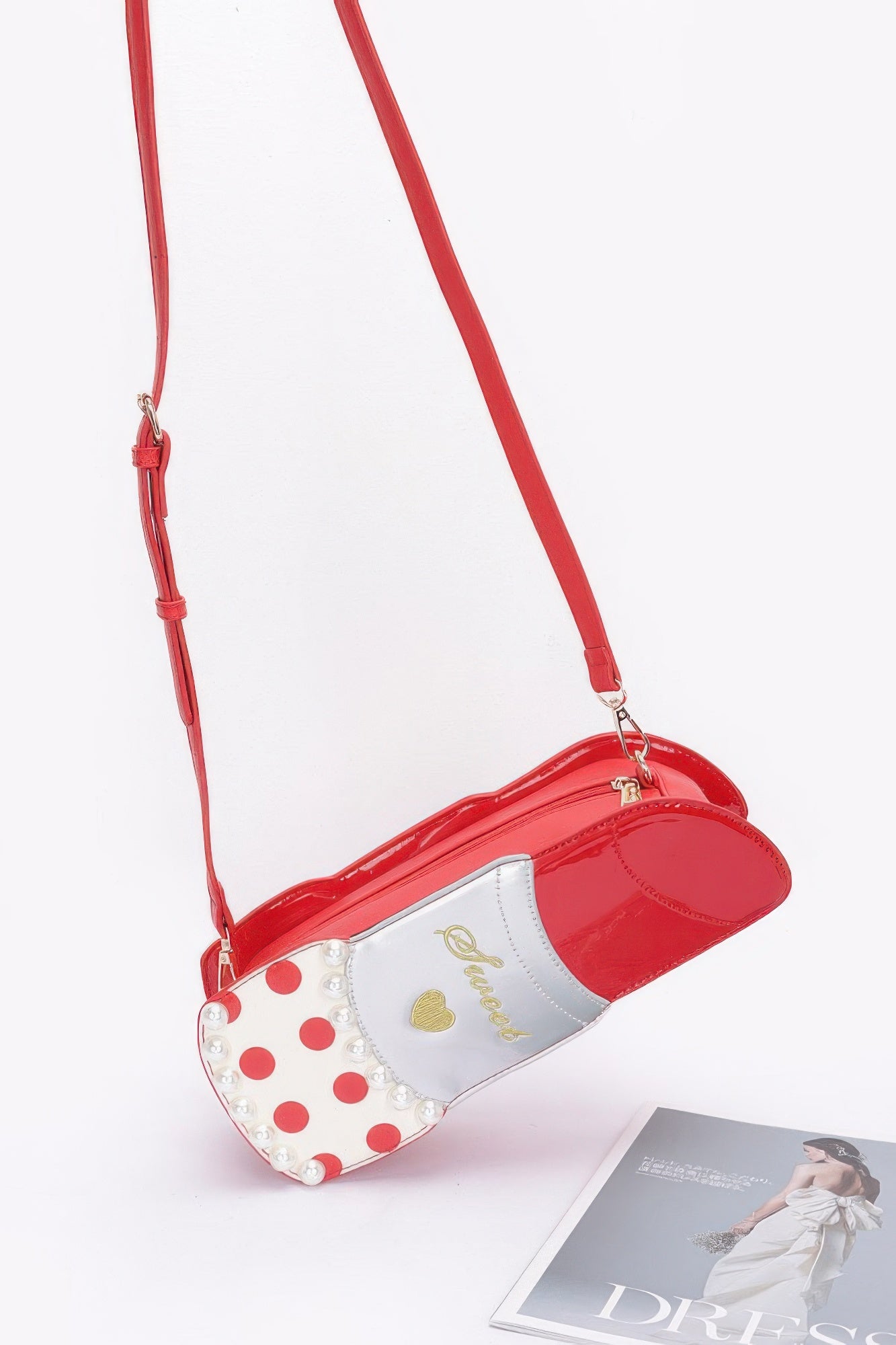 Red lipstick-shaped crossbody bag with adjustable strap and small gold hardware