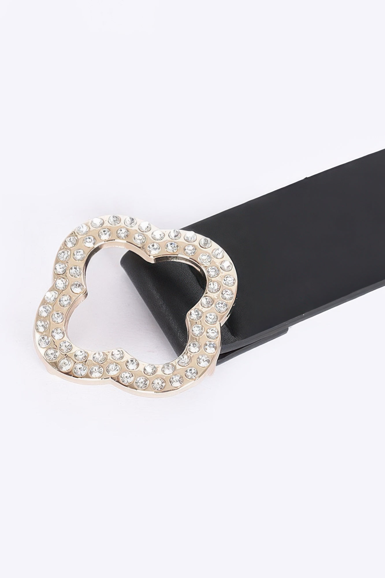 Black belt buckle close-up: rhinestone clover on faux-leather strap