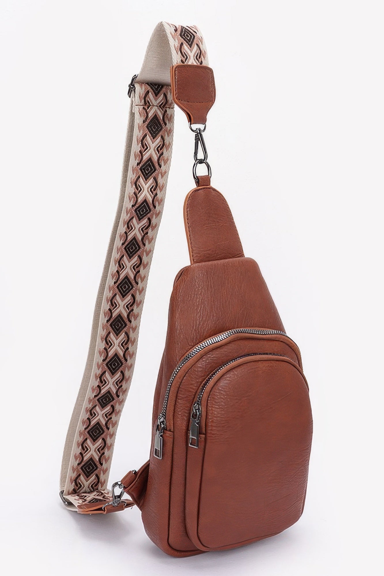 Brown faux leather sling bag with front zip pocket and patterned strap