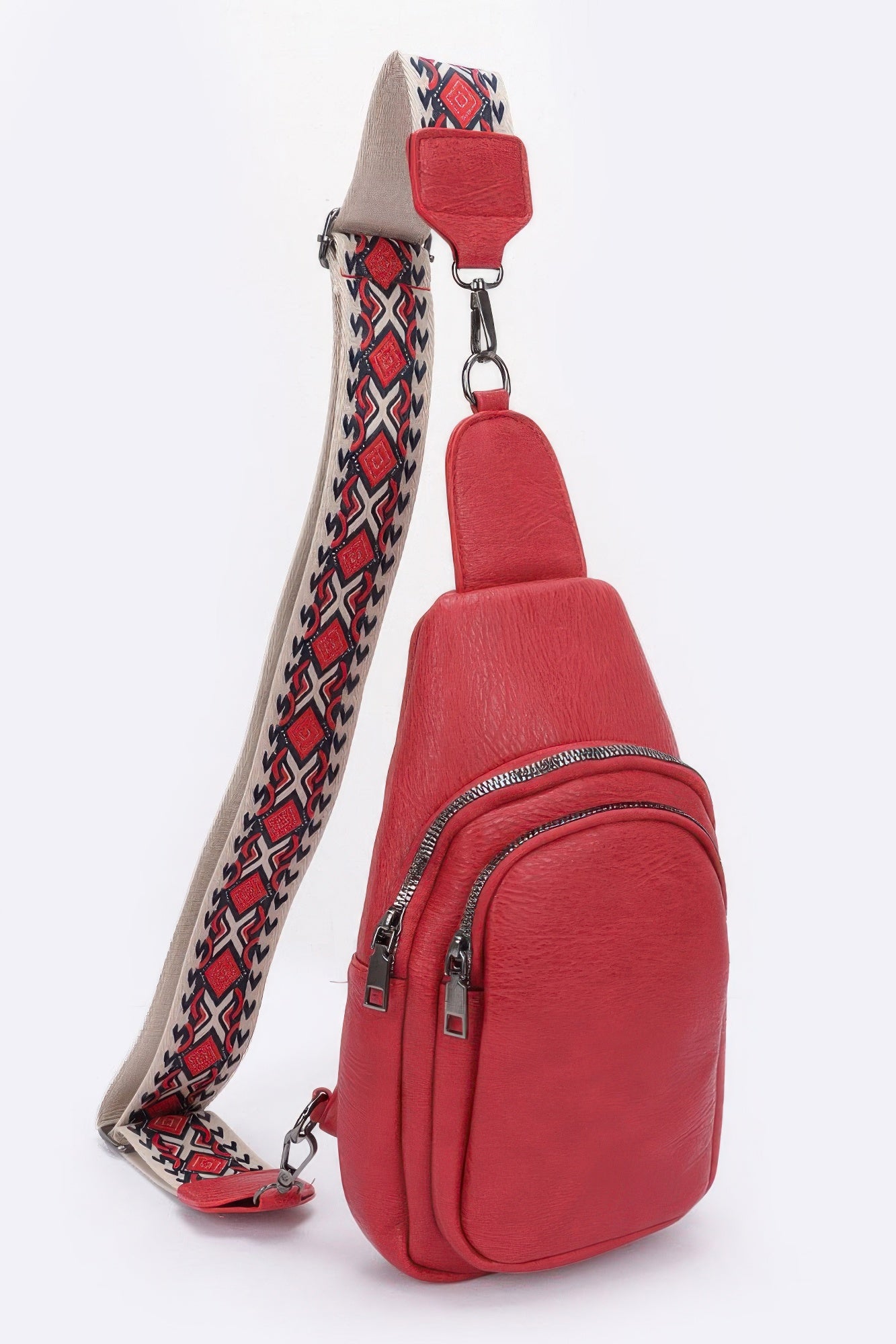Red faux leather sling bag with zip closure and patterned webbing strap