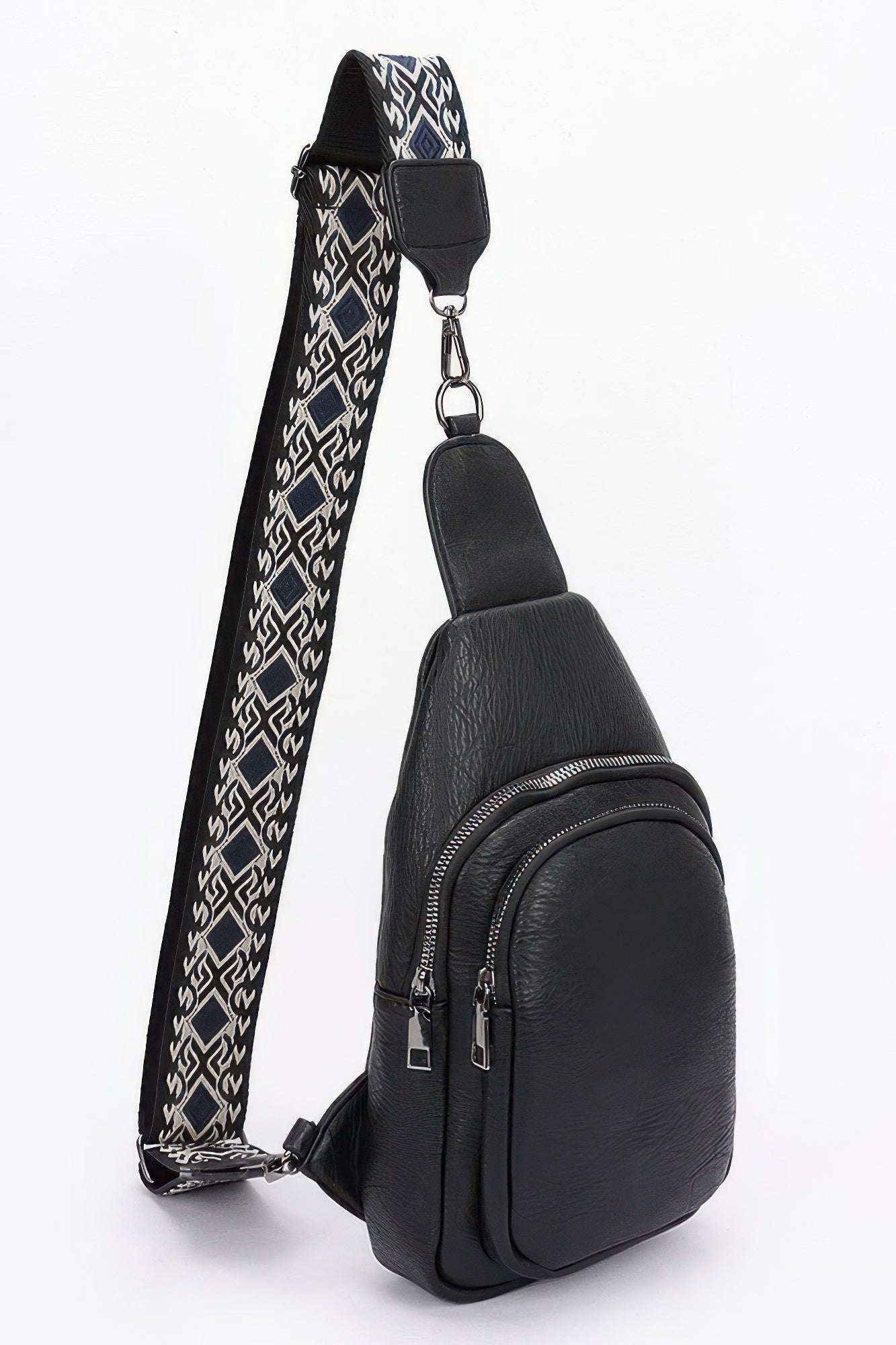 Black faux leather sling bag with front zip pocket and patterned shoulder strap