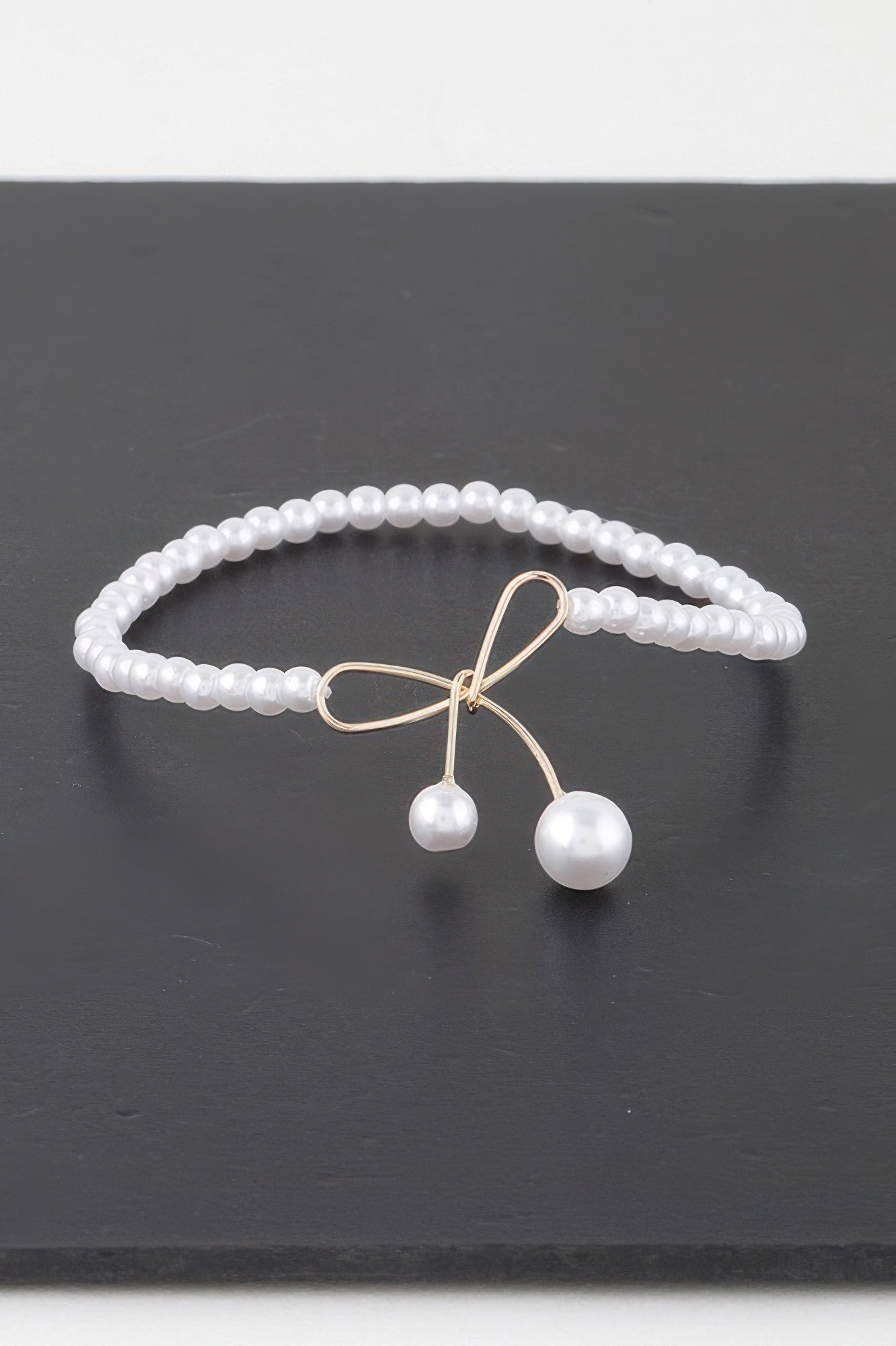 Faux pearl bow bracelet with silver-tone bow clasp and two pearl drop charms