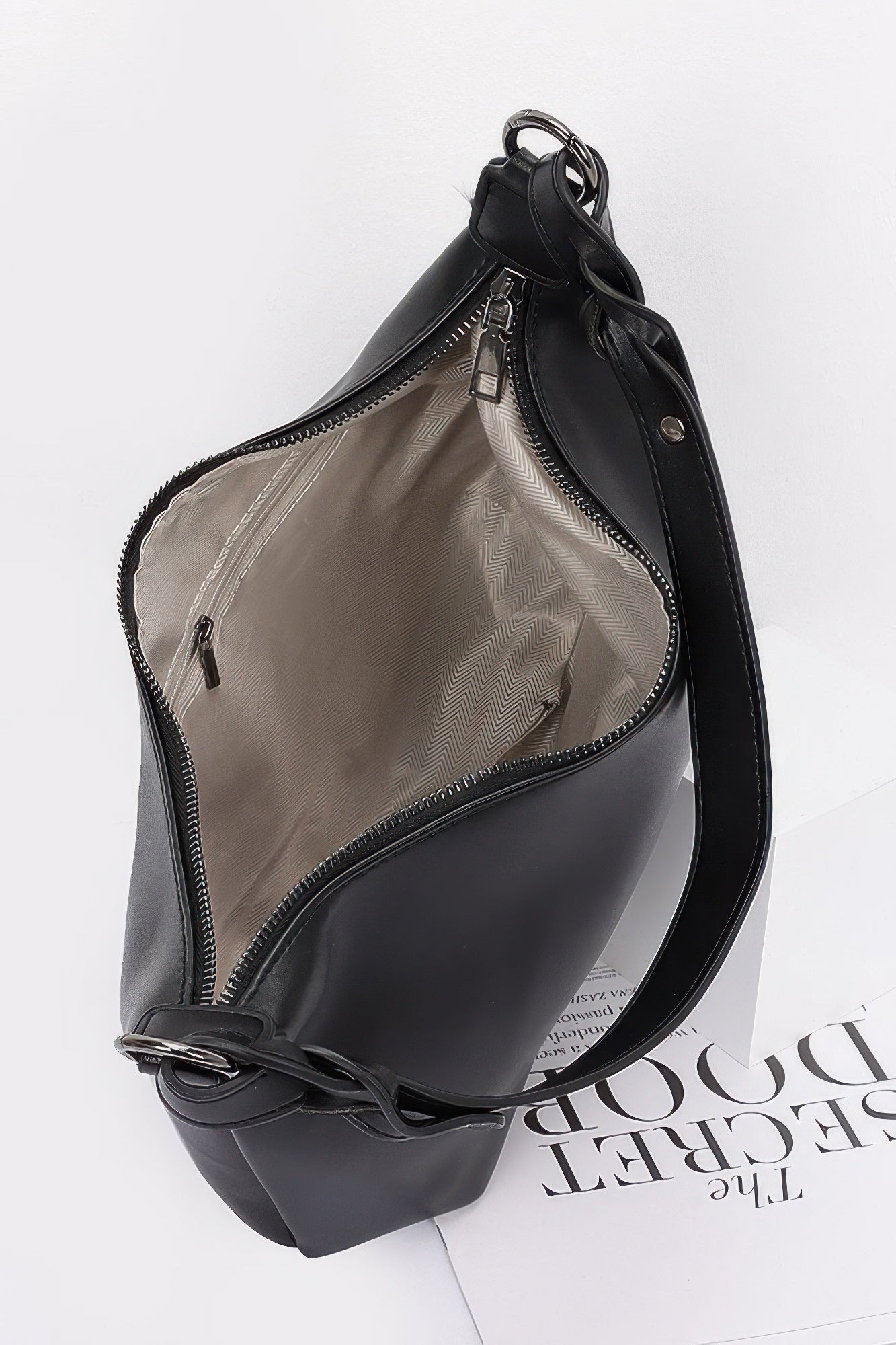 Black shoulder bag with open top showing inner pocket and zip fastening
