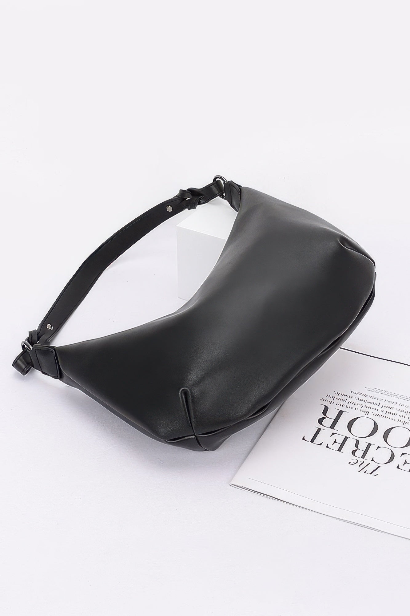 Black faux strap shoulder bag with slouchy hobo shape and side seam