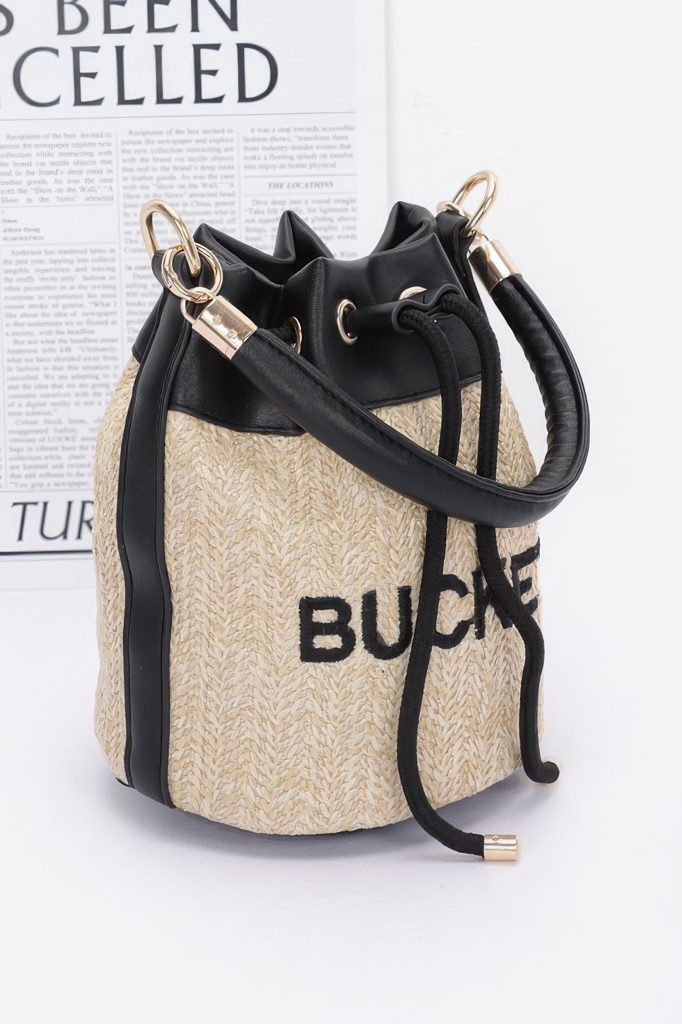 Faux straw bucket bag, black crossbody strap, camel woven sides with eyelets