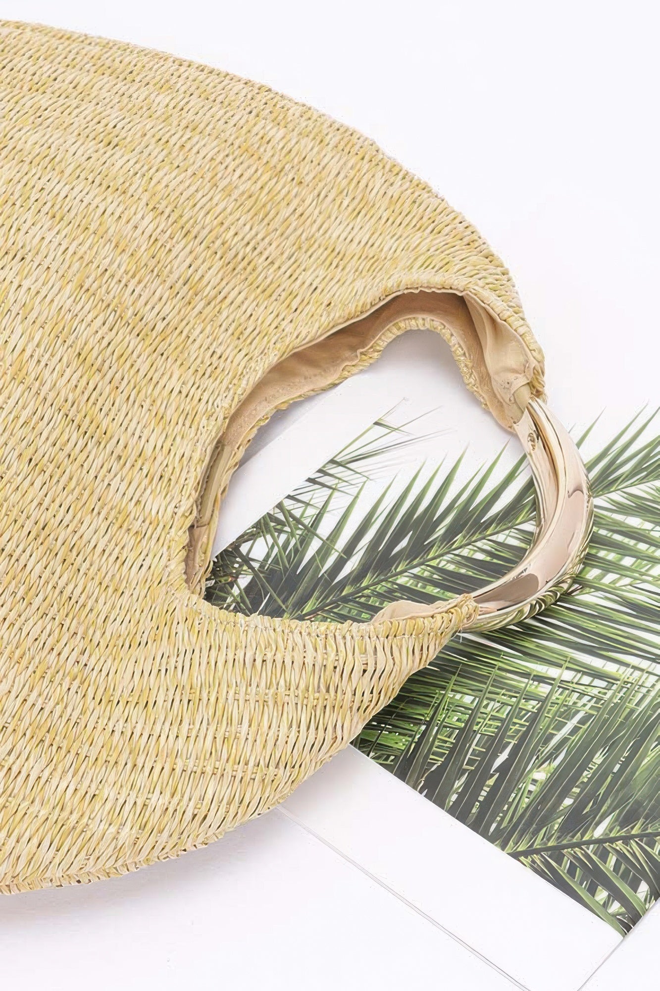 Close-up of khaki faux straw hobo bag handle and stitched opening