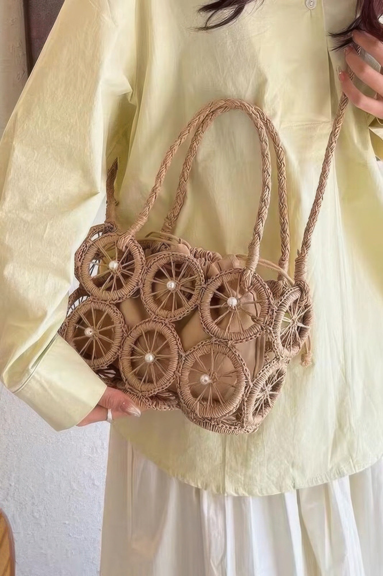 Khaki faux straw round crossbody bag with braided handles and wheel motifs
