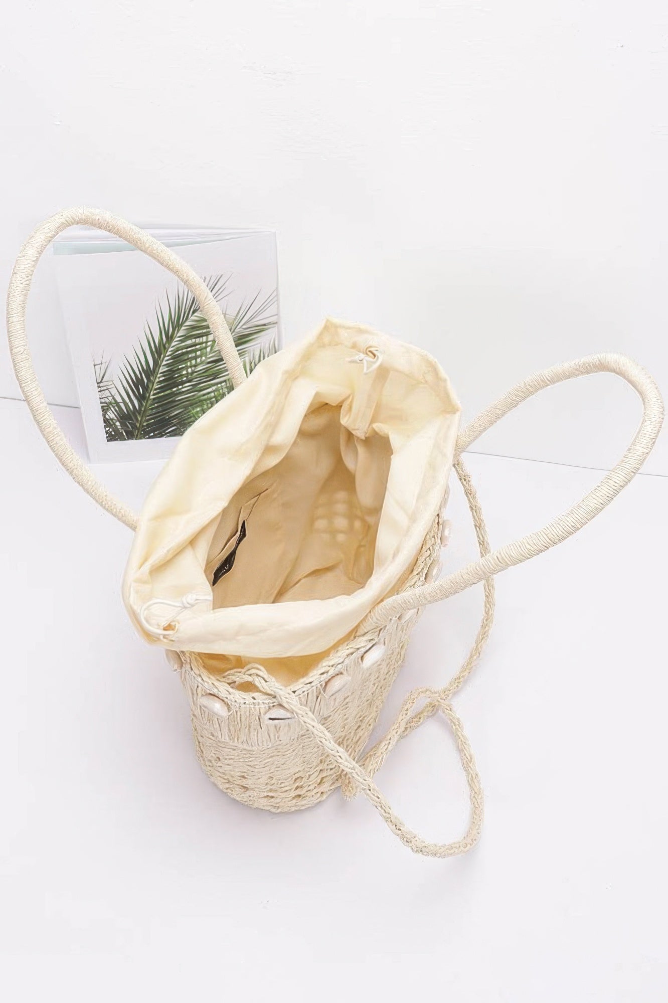 Ivory faux straw shell tote bag with open top and light fabric lining inside