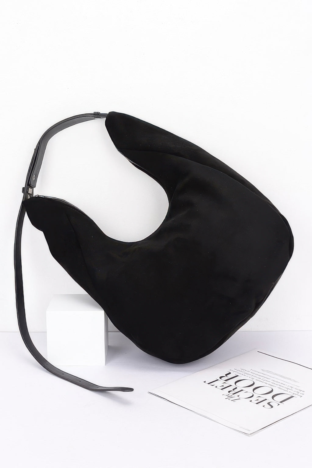 Black faux suede bindle bag with front curve and long crossbody strap