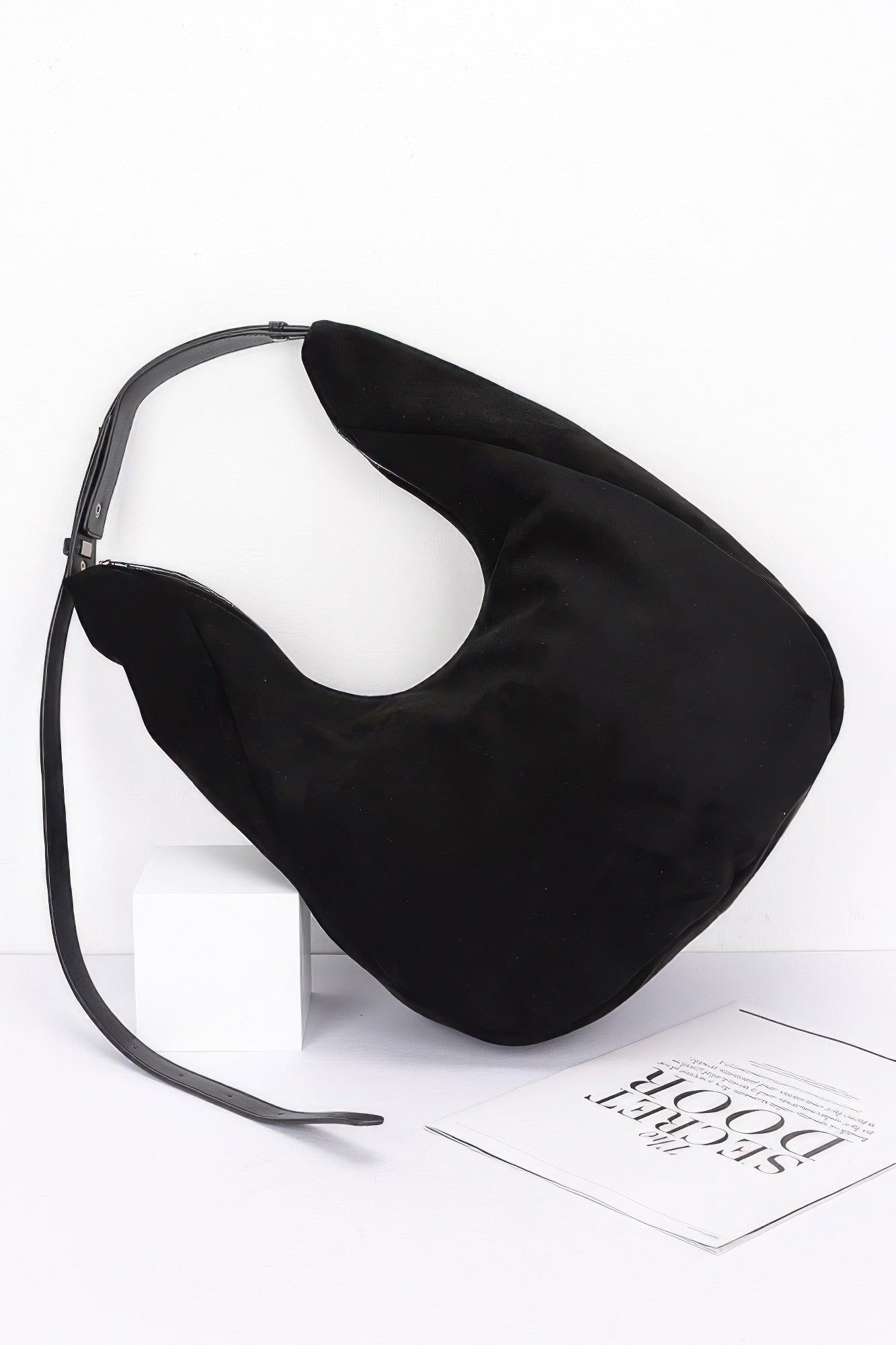 Black faux suede bindle bag with front curve and long crossbody strap