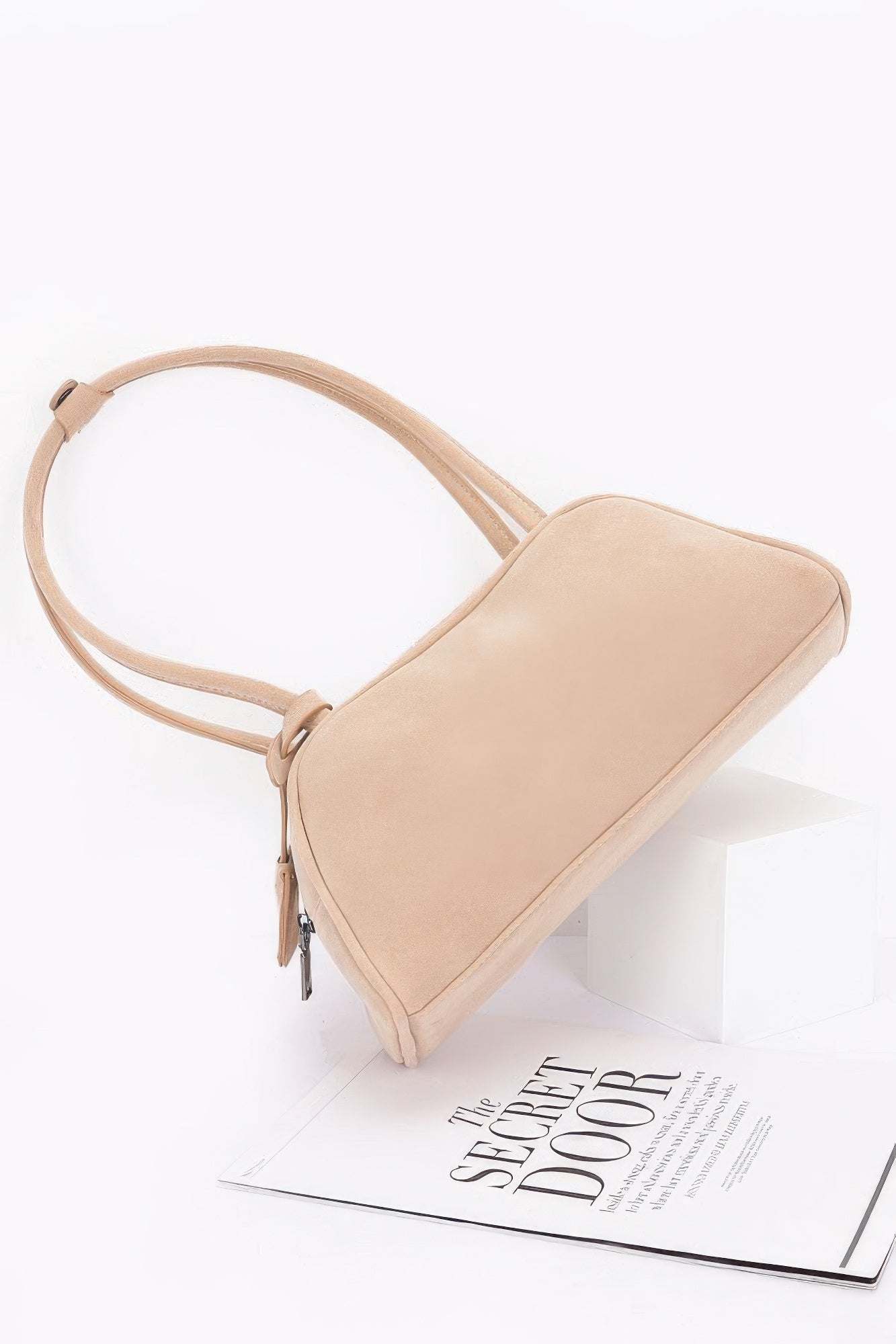Beige faux suede sport bag angled view with curved handle and zip detail