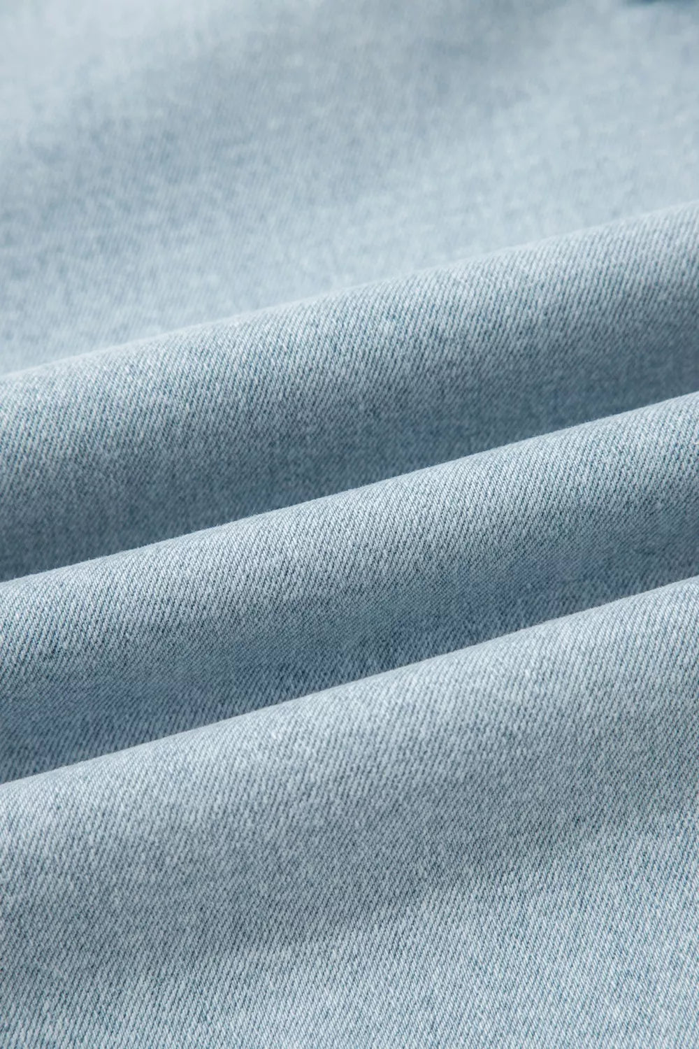 Close-up of light blue denim texture with subtle faded stripes