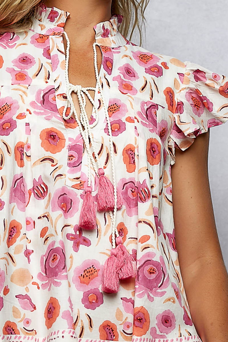 Pink floral blouse close-up: tassel tie cords with ruffled flutter sleeve