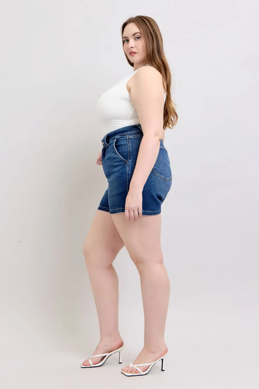 Dark denim shorts with cuffed hem, front pockets, and belt-loop waist, profile