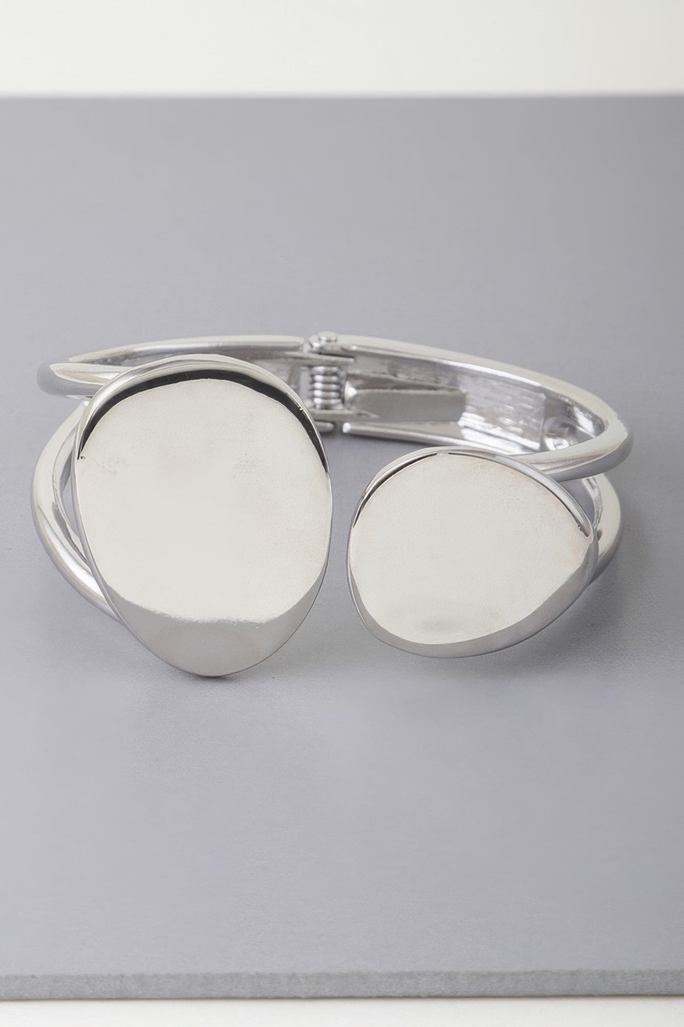 Silver tone cuff bracelet with two round flat discs and open ends