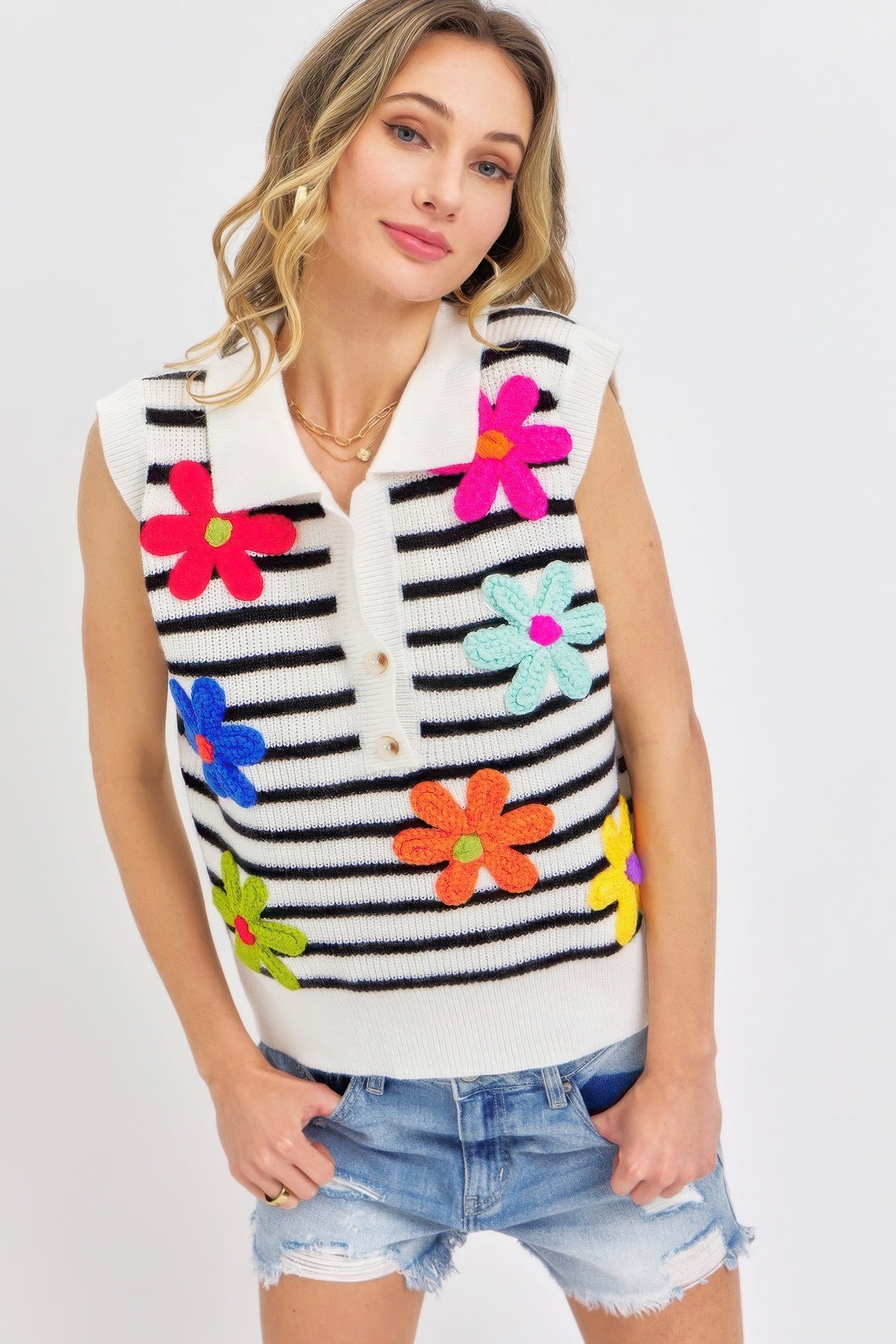 Ivory-and-black striped knit top, sleeveless, with colorful flower appliqués and buttons