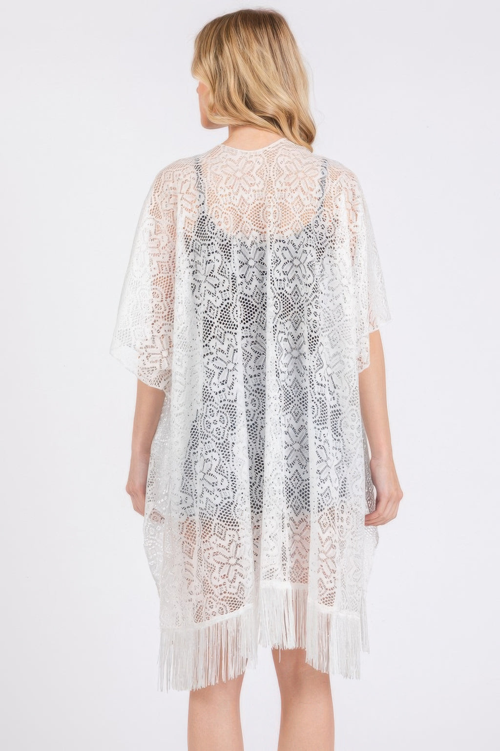 Back view of white crochet lace cover up with vertical floral pattern and tassel hem