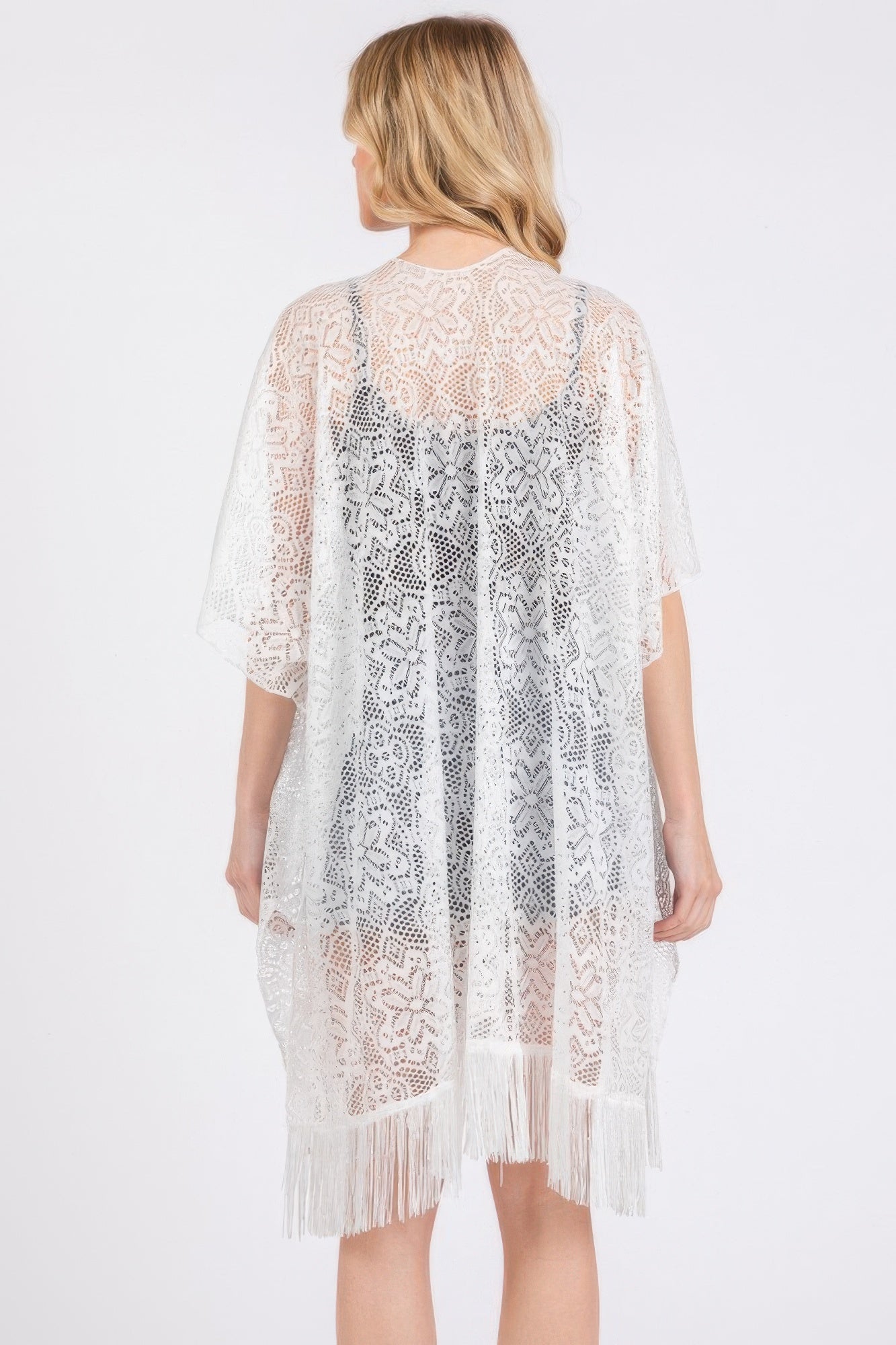 Back view of white crochet lace cover up with vertical floral pattern and tassel hem