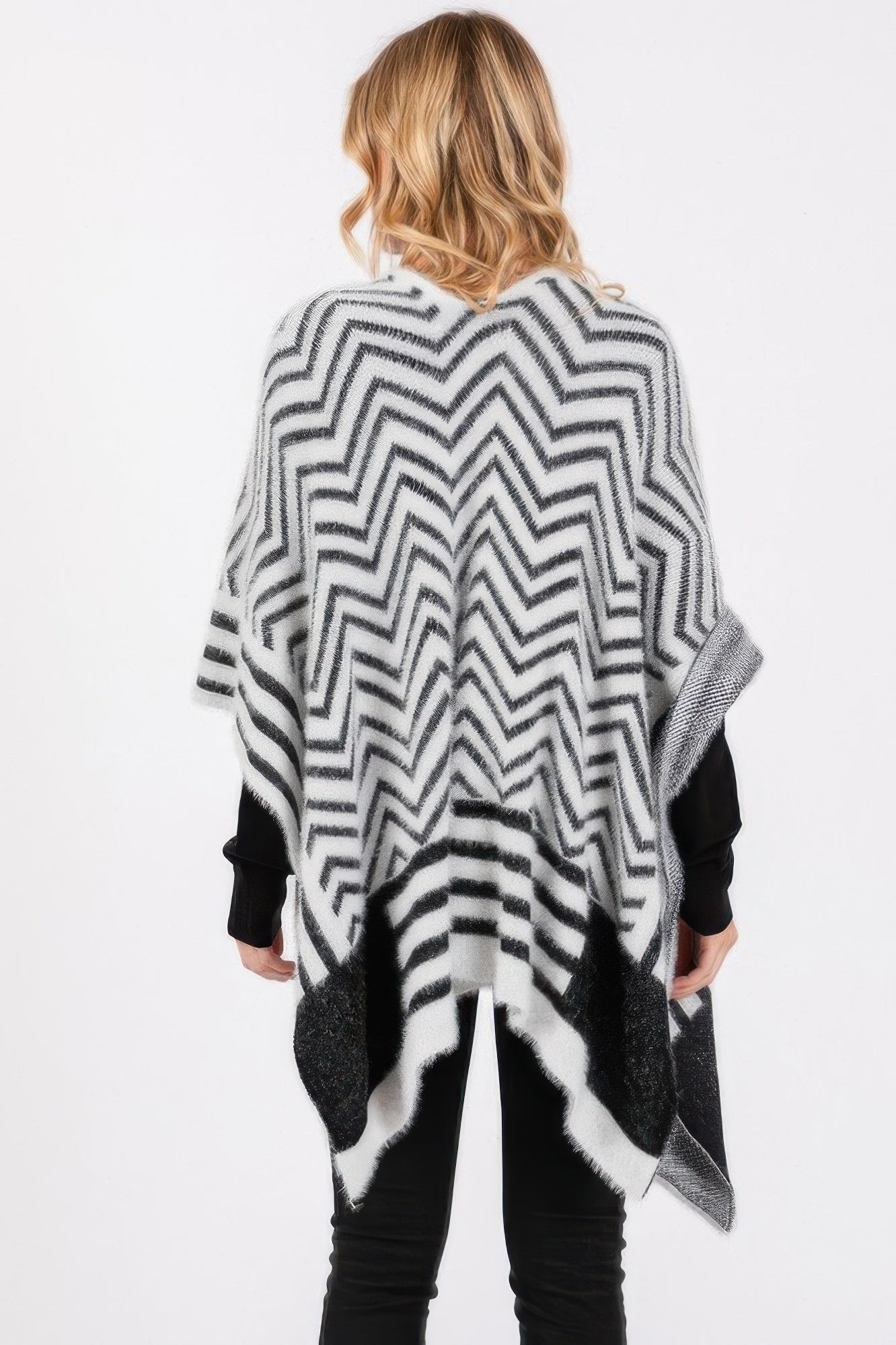Back view: fuzzy chevron ruana in ivory/black with bold zigzag design and fringe