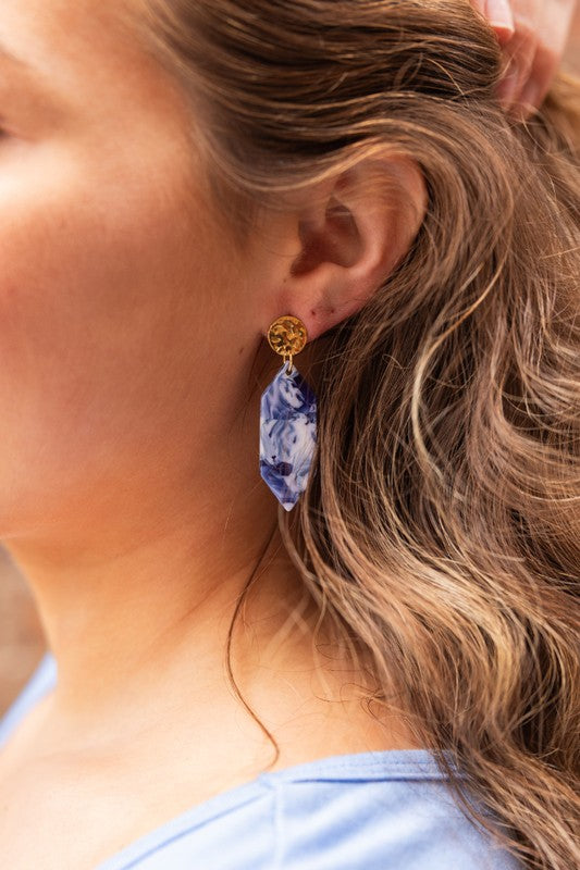 Blue ocean-wave dangle earrings with gold round studs, worn on the ear