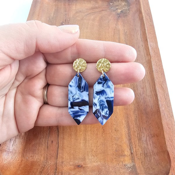 Gemma earrings in hand: gold round posts with blue ocean-wave teardrop dangles