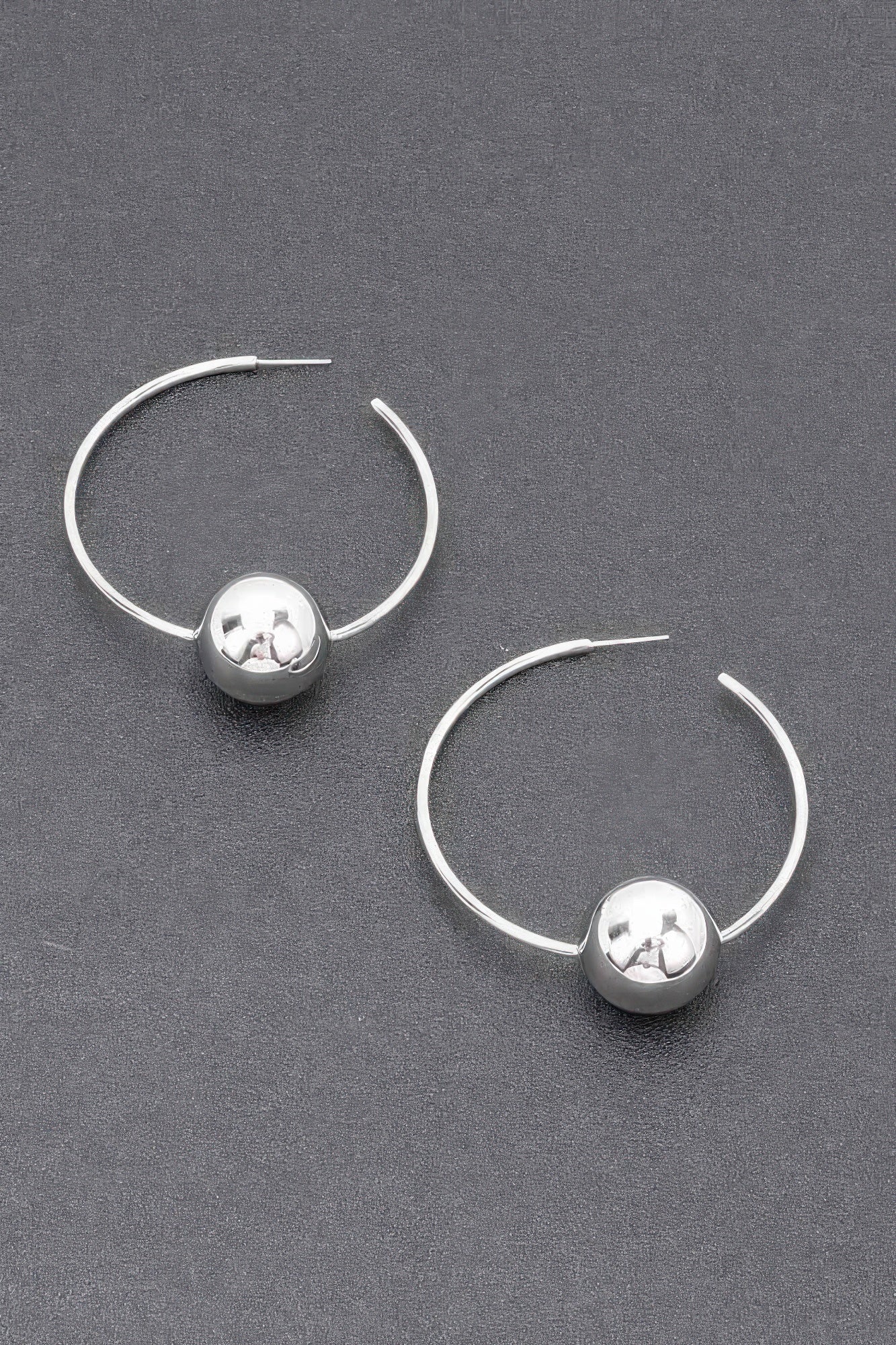 Silver hoop earrings with round ball charm and reflective star-pattern detail