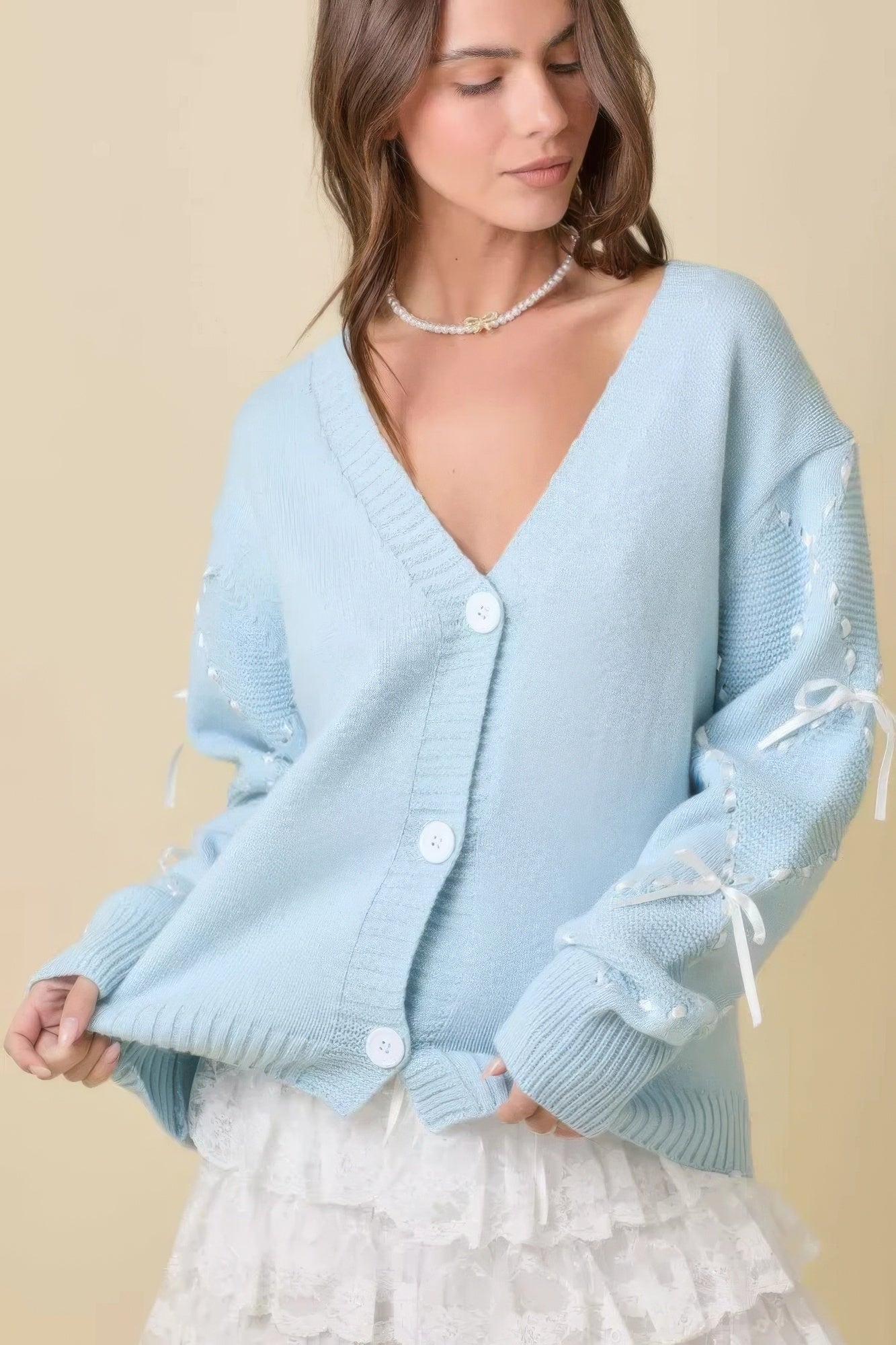 Light blue cardigan con botones frontales y detalle tipo satén en las mangas con lazos