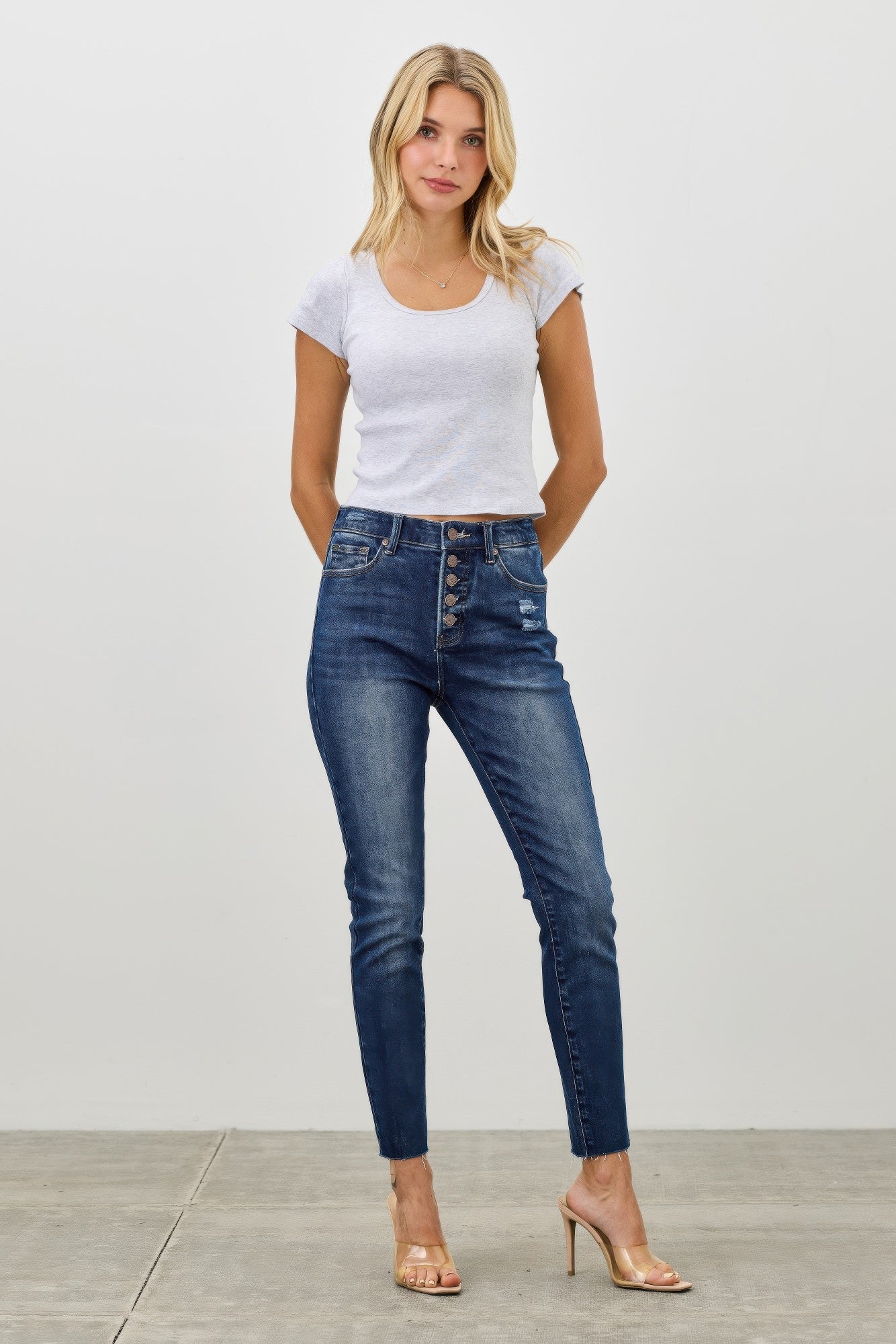 Dark blue high-rise ankle skinny jeans with button-fly and distressed knee