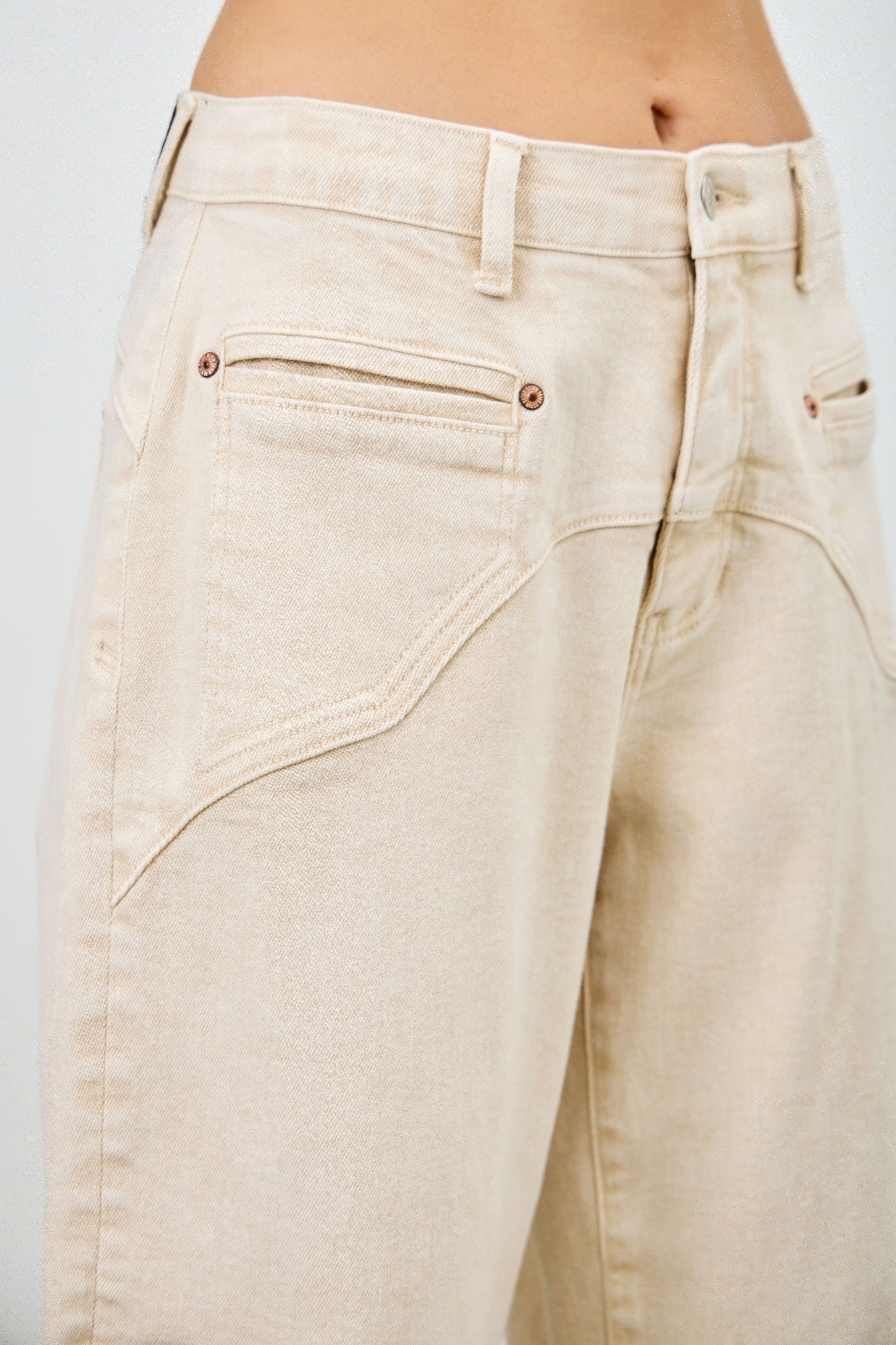 Detailansicht High-rise western jeans: vordere Taschen, braune Ziernähte, cremefarbener Denim