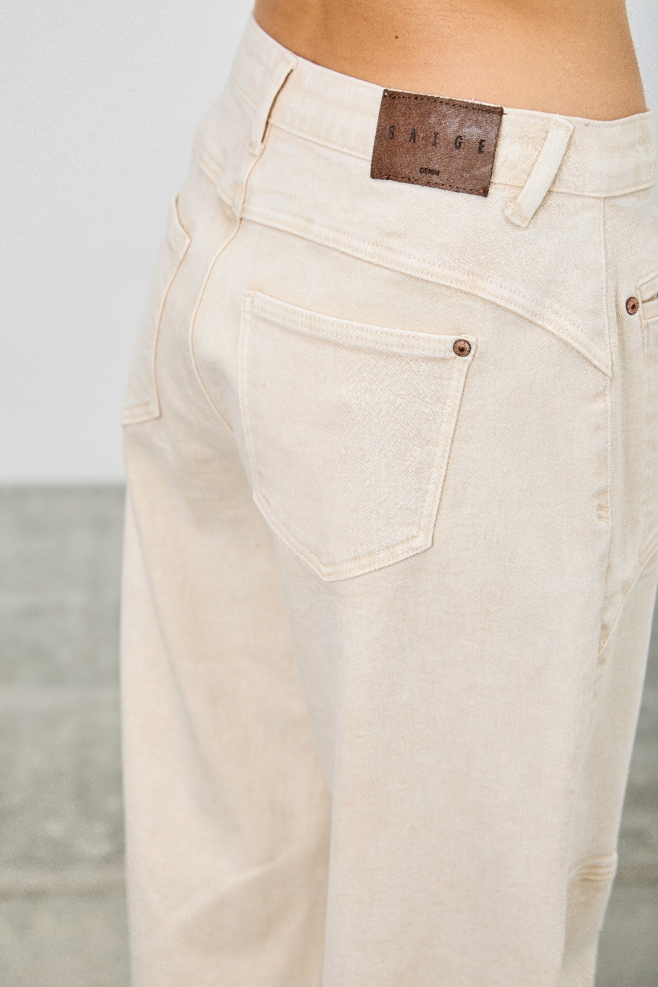 Detail: High-rise barrel jeans mit hinterer Gesäßtasche, cremefarbener Oberfläche und Markenlabel
