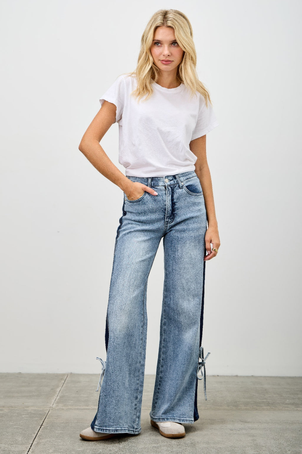 High-rise wide-leg jeans in medium wash with contrast panels and ribbon hem ties