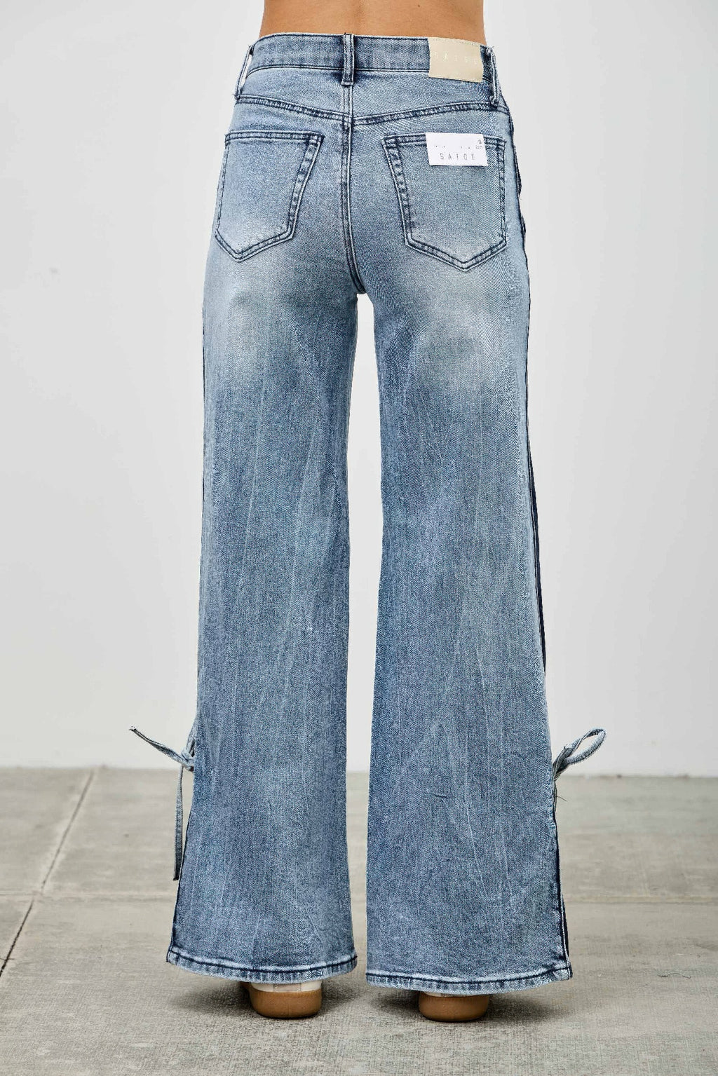 Back view wide-leg jeans in light wash, ribbon ties at sides, high rise