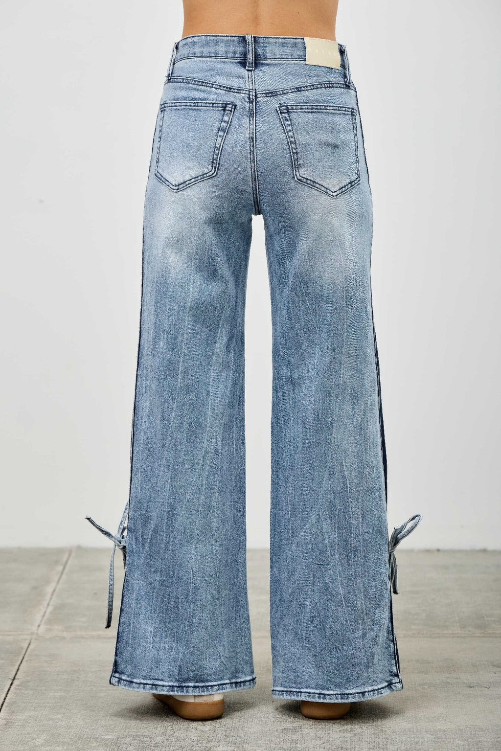 Back view high-rise wide-leg jeans in light wash denim, side ribbon ties