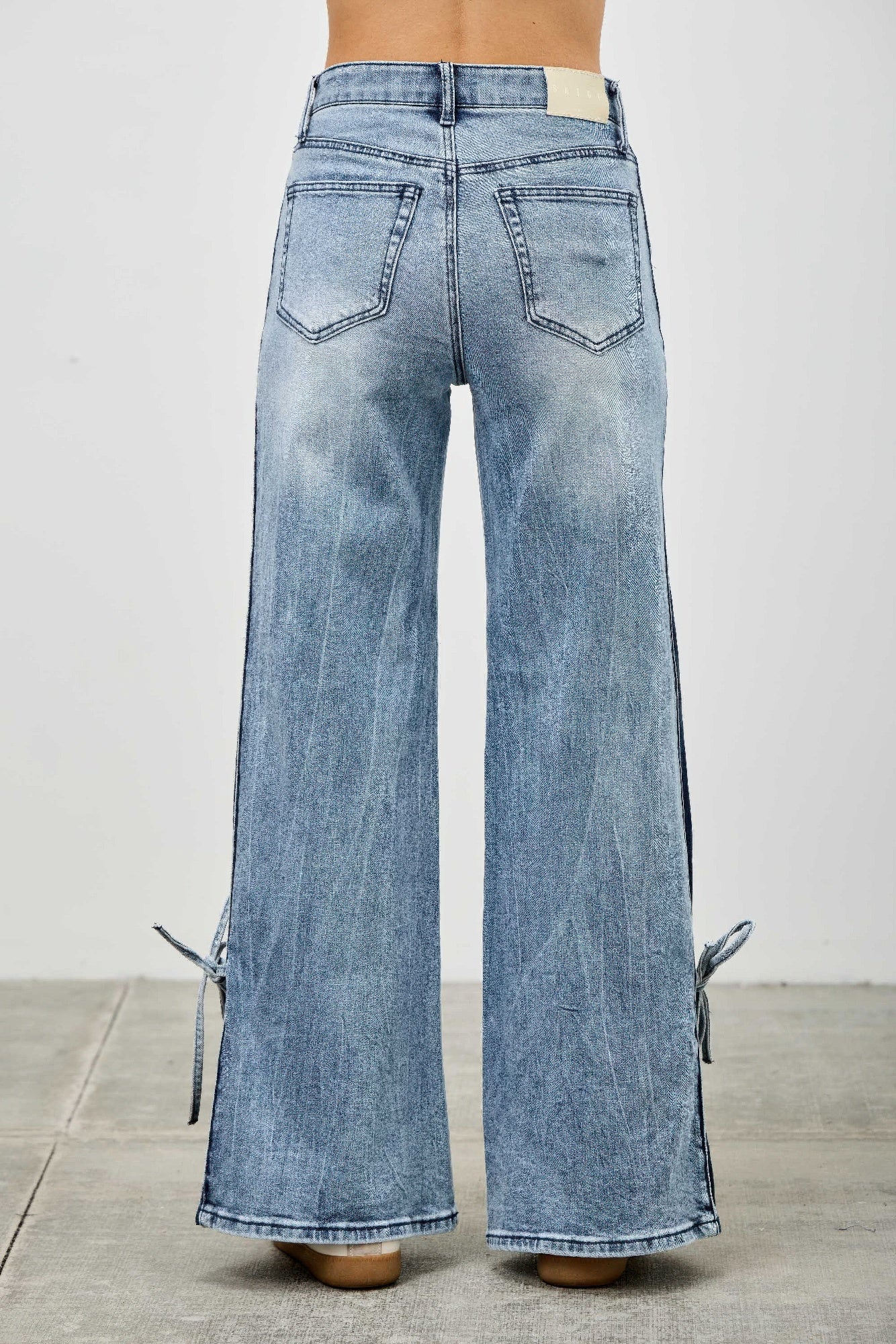 Back view high-rise wide-leg jeans in light wash denim, side ribbon ties
