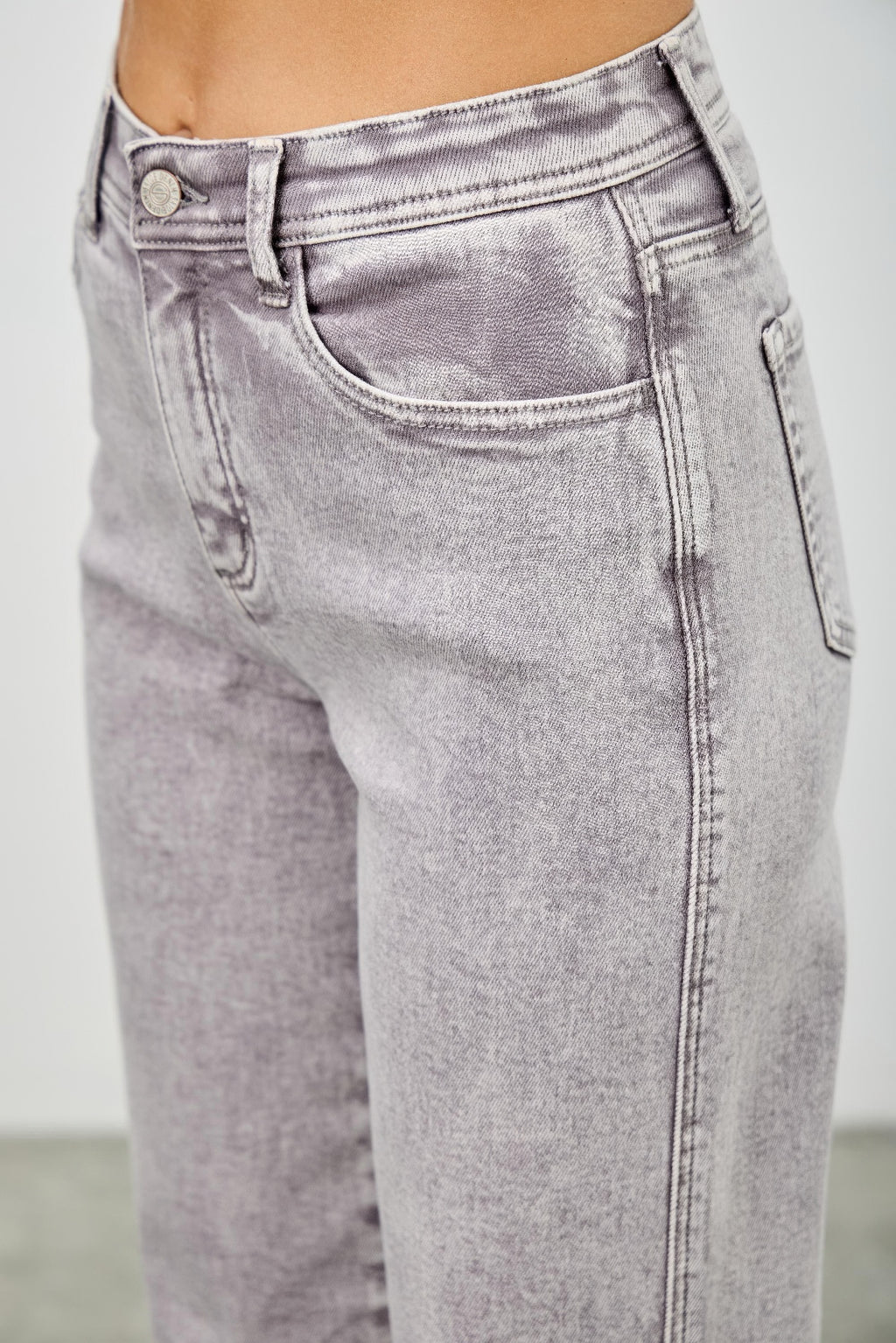 Close-up: light gray high rise denim jeans with belt loops, button fly, and back yoke.