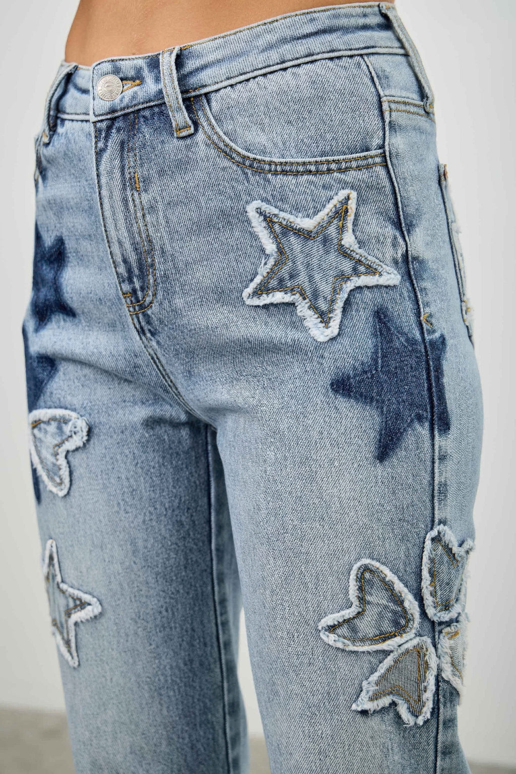 Close-up: high-rise dad jeans with stitched star patches and heart patches on denim