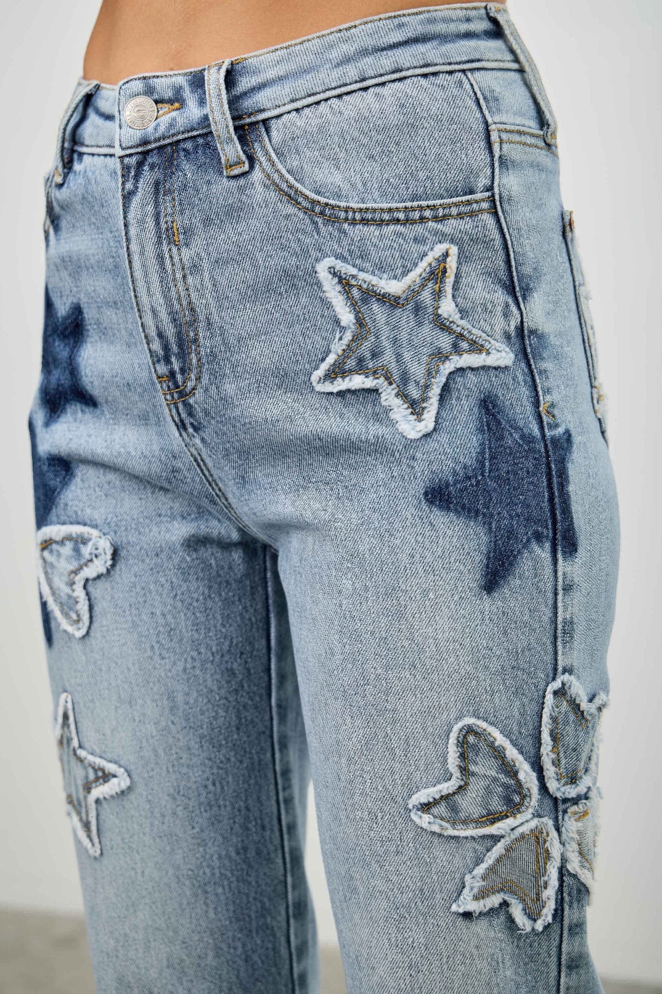 Close-up: high-rise dad jeans with stitched star patches and heart patches on denim