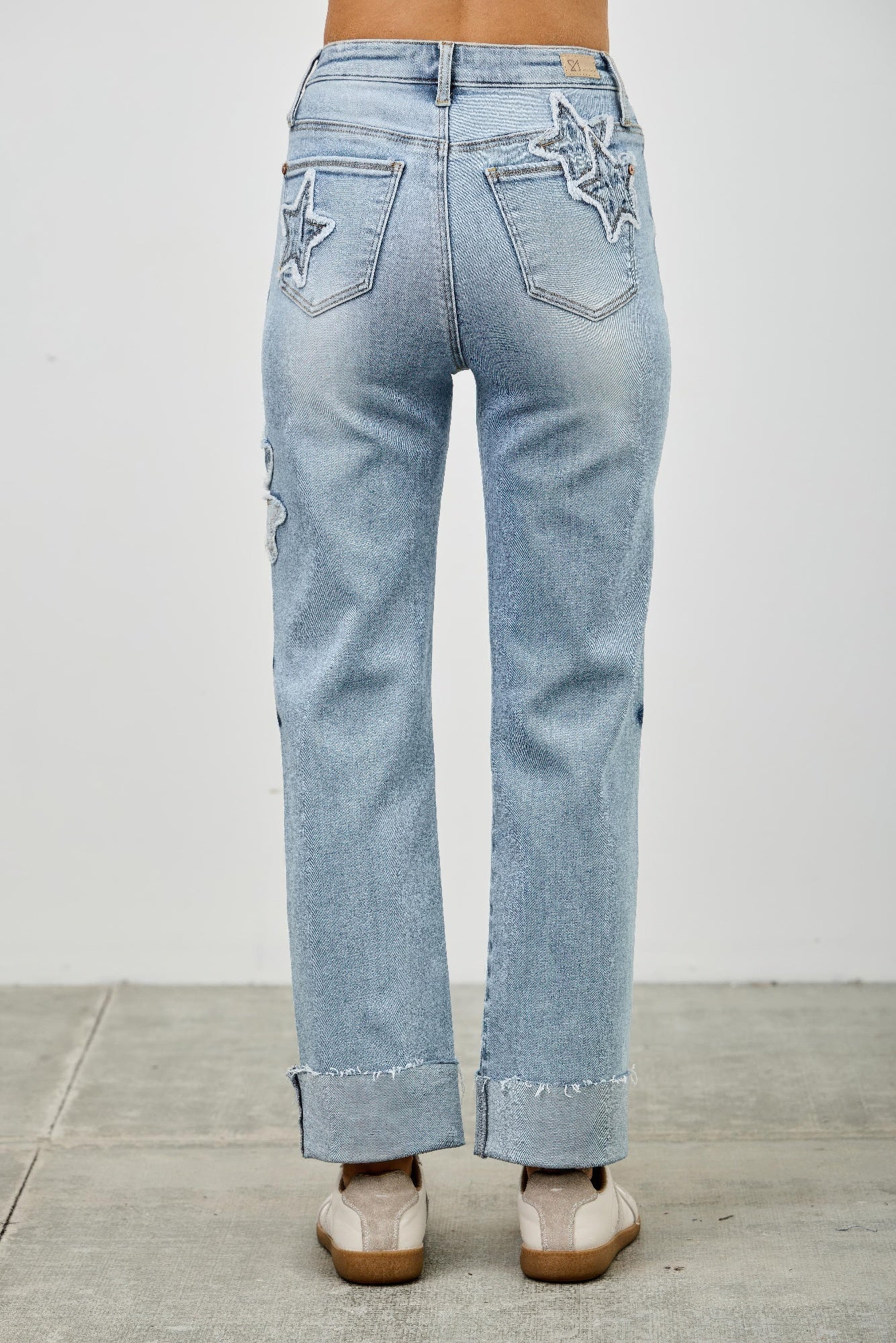 High-rise dad jeans with star patches and raw, rolled hem at the ankles
