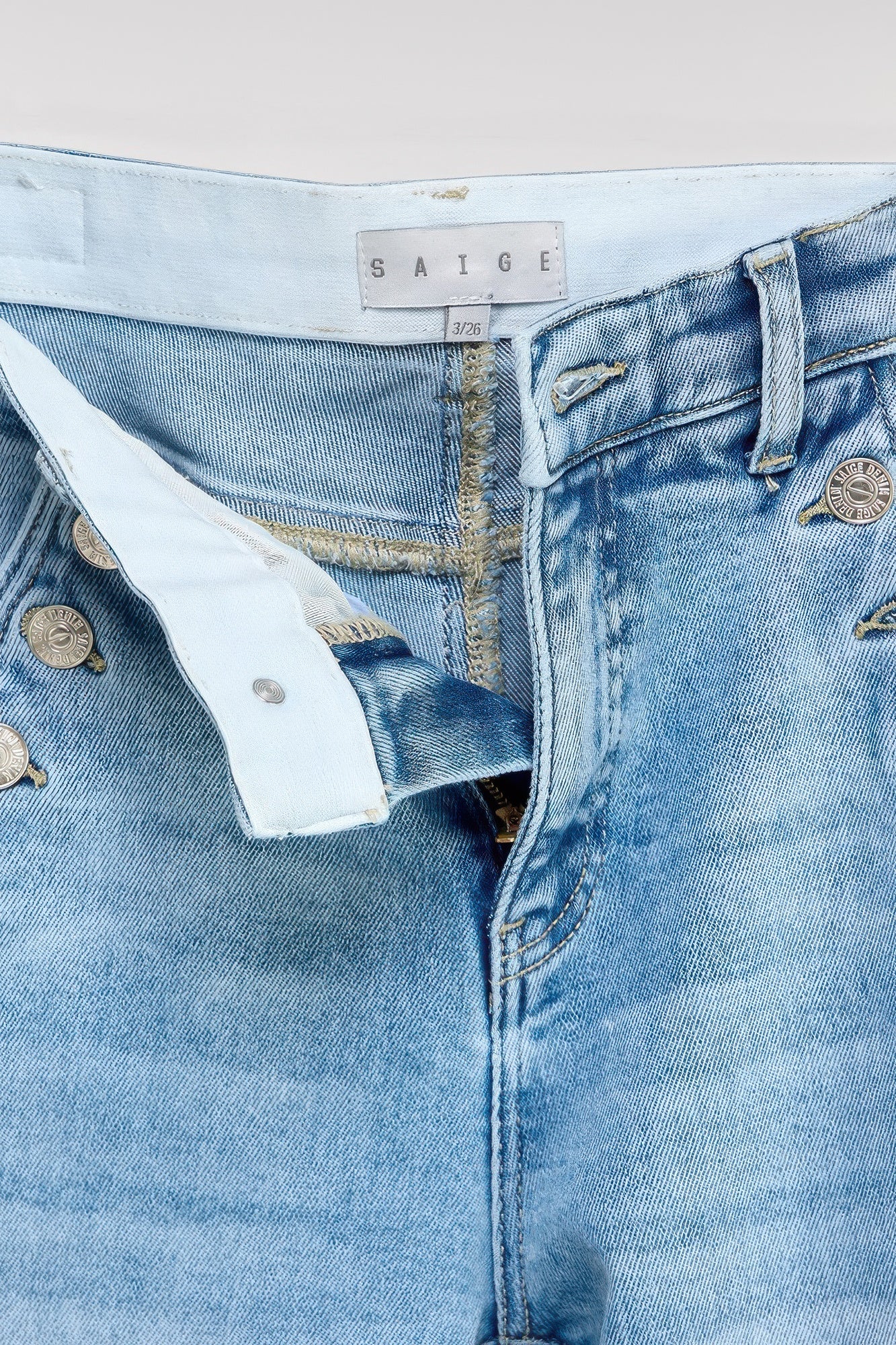 Button pocket jeans: waistband label and front button close-up on light blue denim