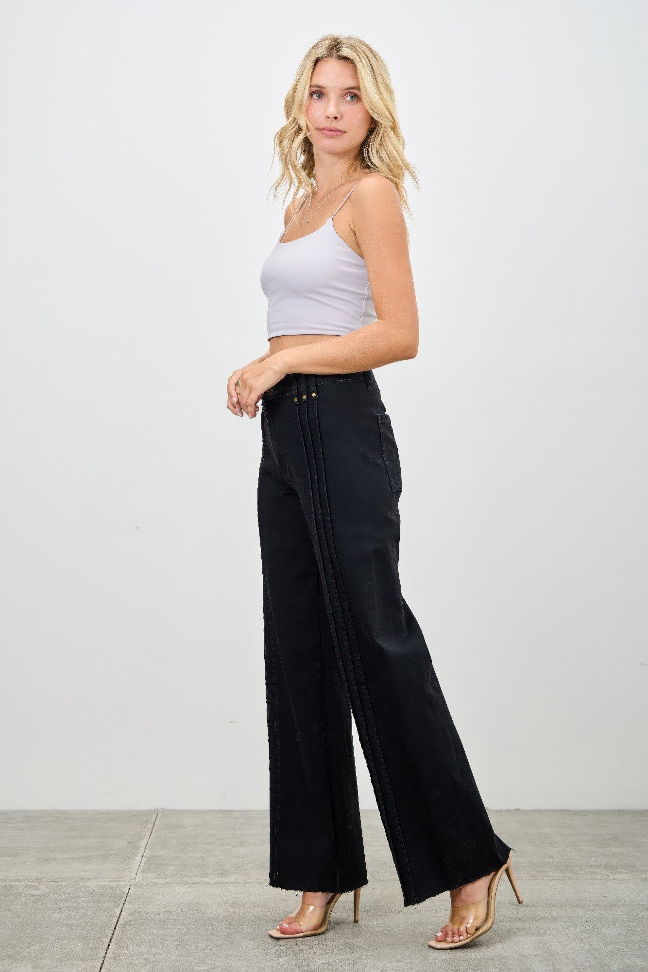 Side view of high-rise straight black jeans with vertical seams and long straight leg