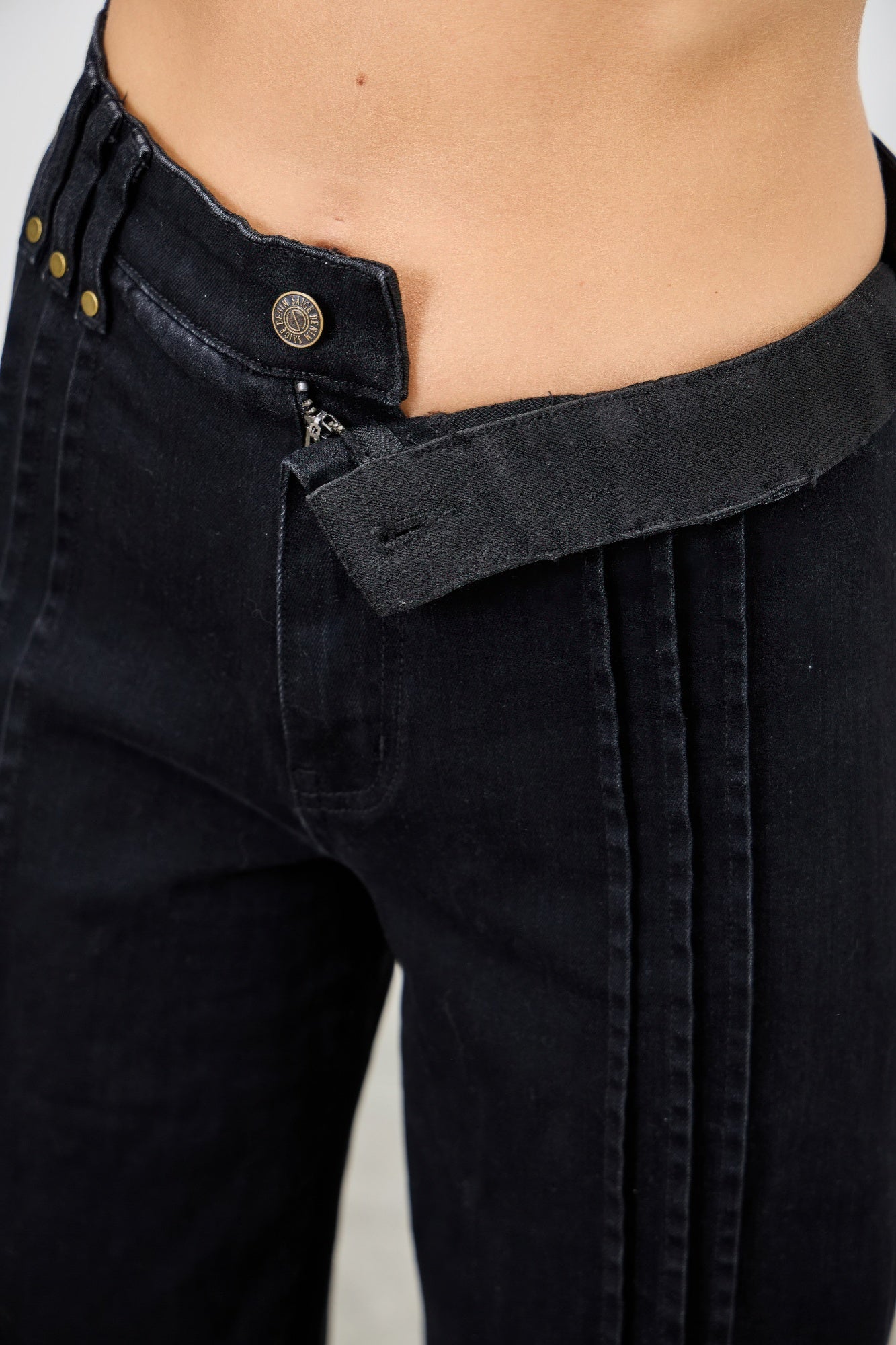 Close-up: high-rise dark black denim waistband with button closure and belt loops