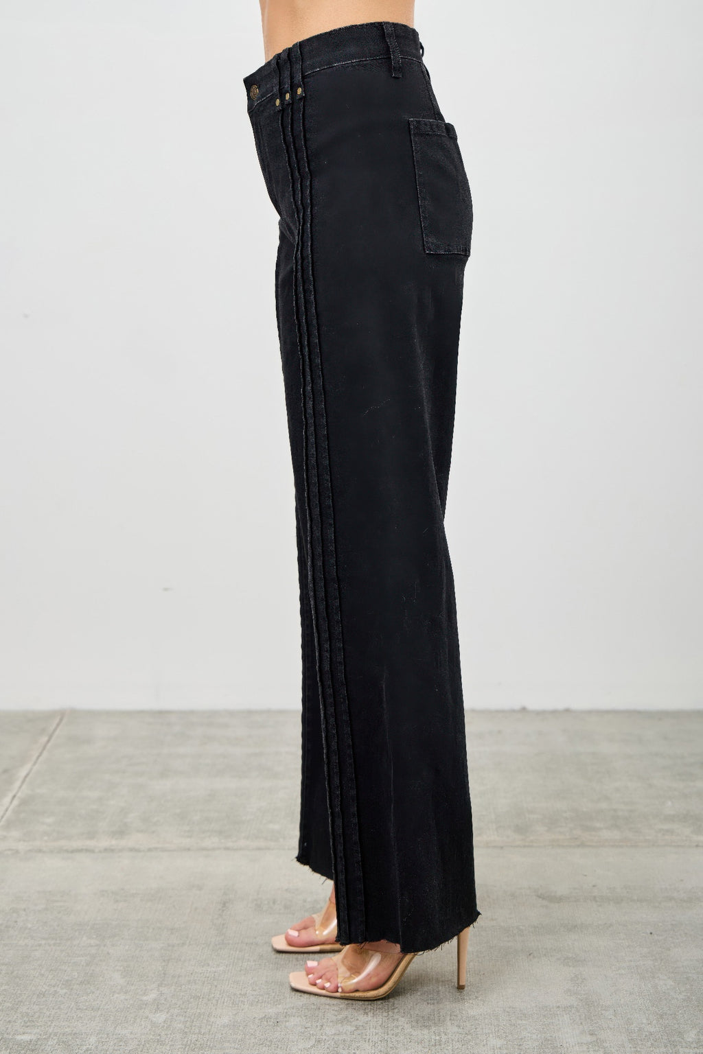 Side view of high-rise straight black jeans with side pocket and vertical seam detailing