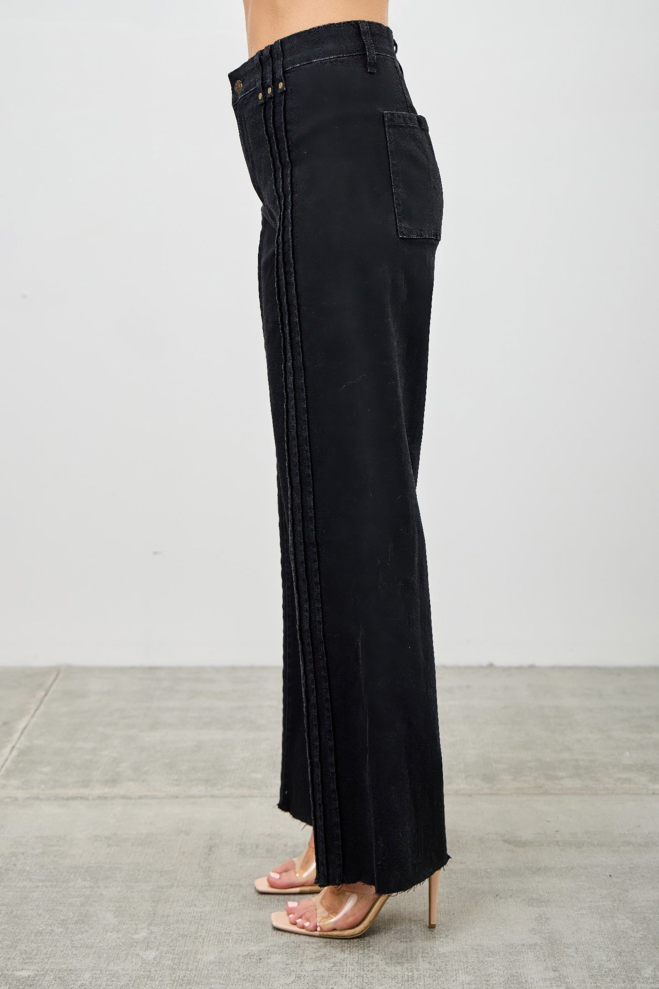 Side view of high-rise straight black jeans with side pocket and vertical seam detailing