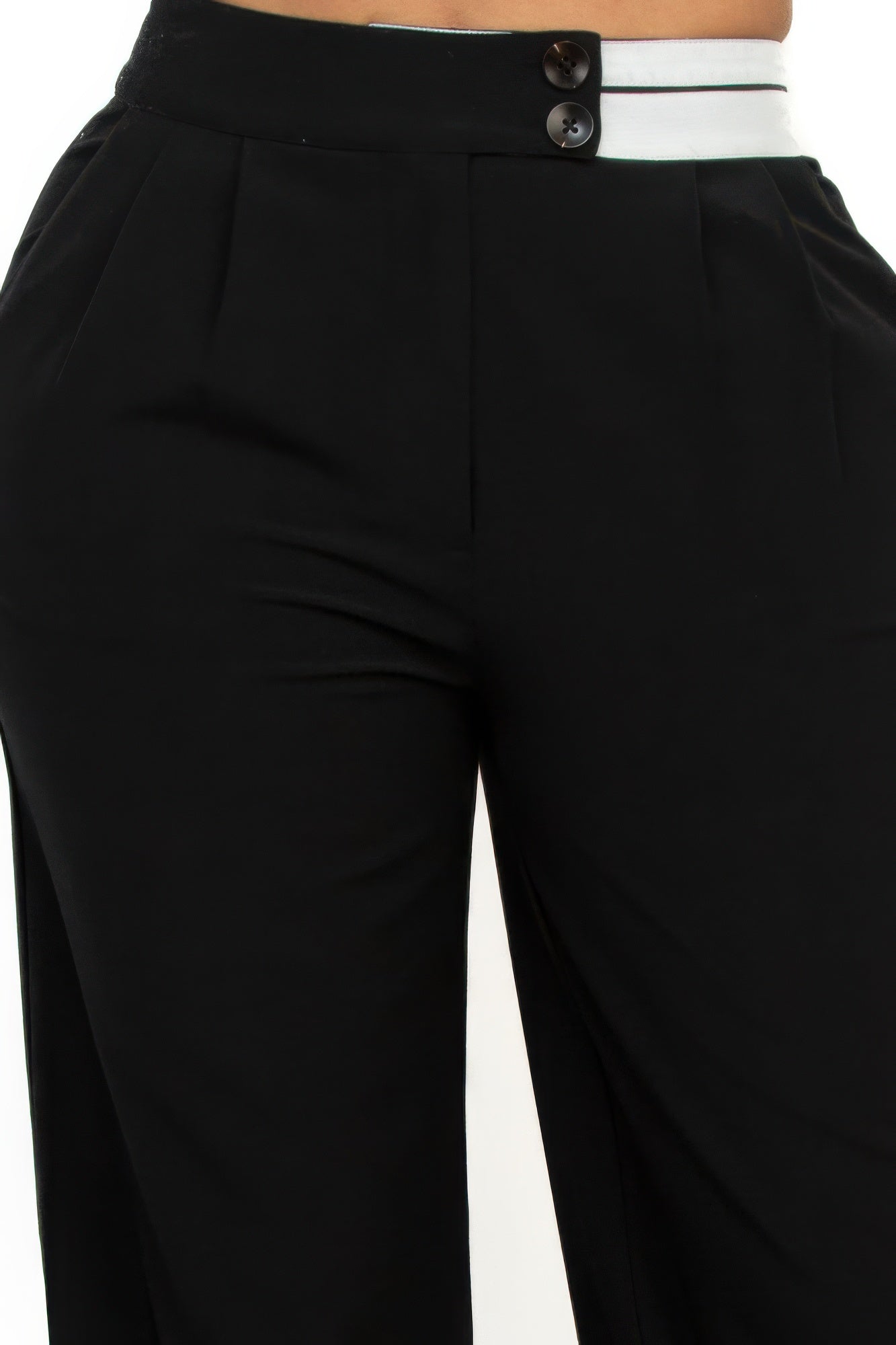 Close-up: black high-rise pants with contrast waistband and two dark buttons