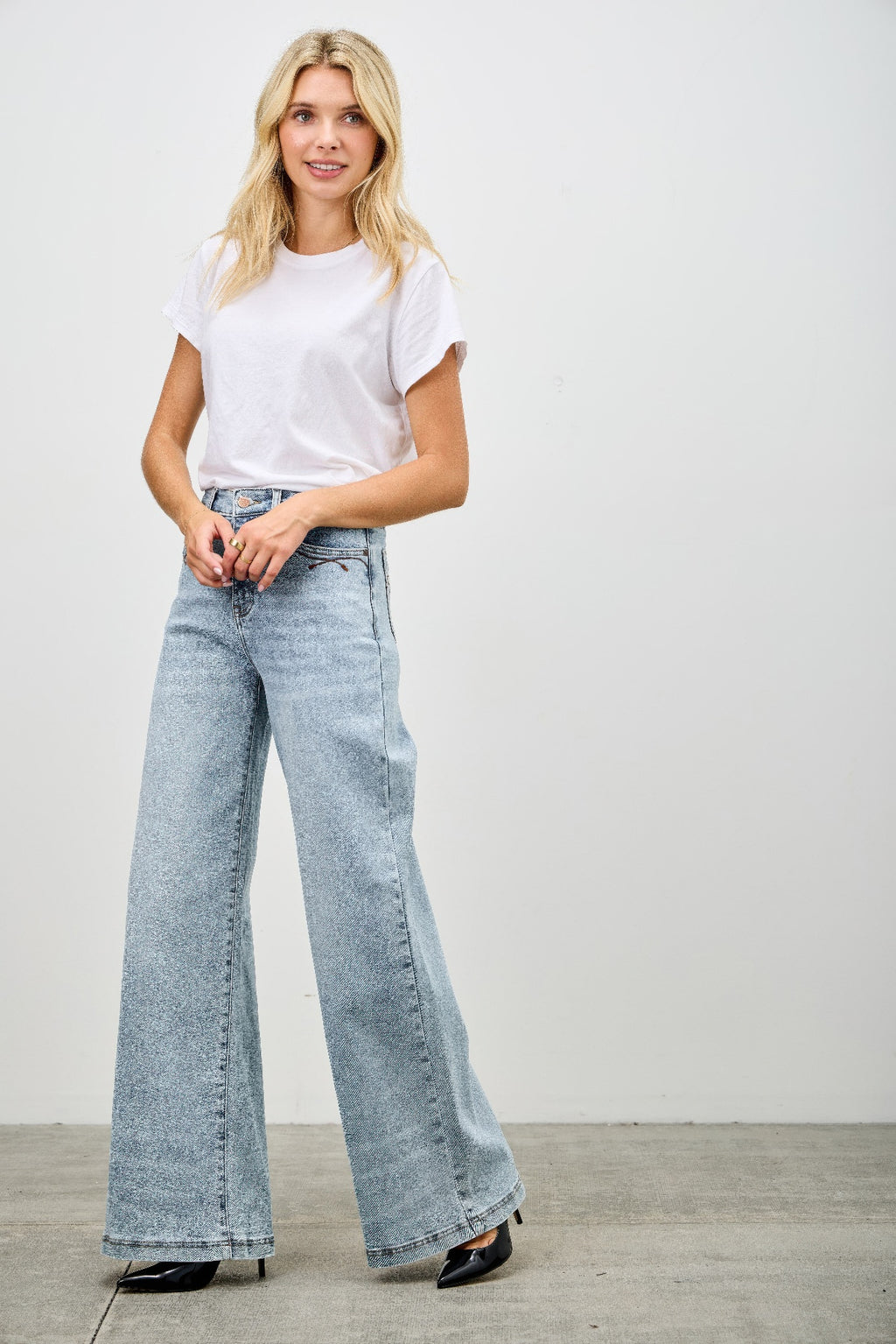 High rise wide-leg jeans on model, light blue denim flare with button closure