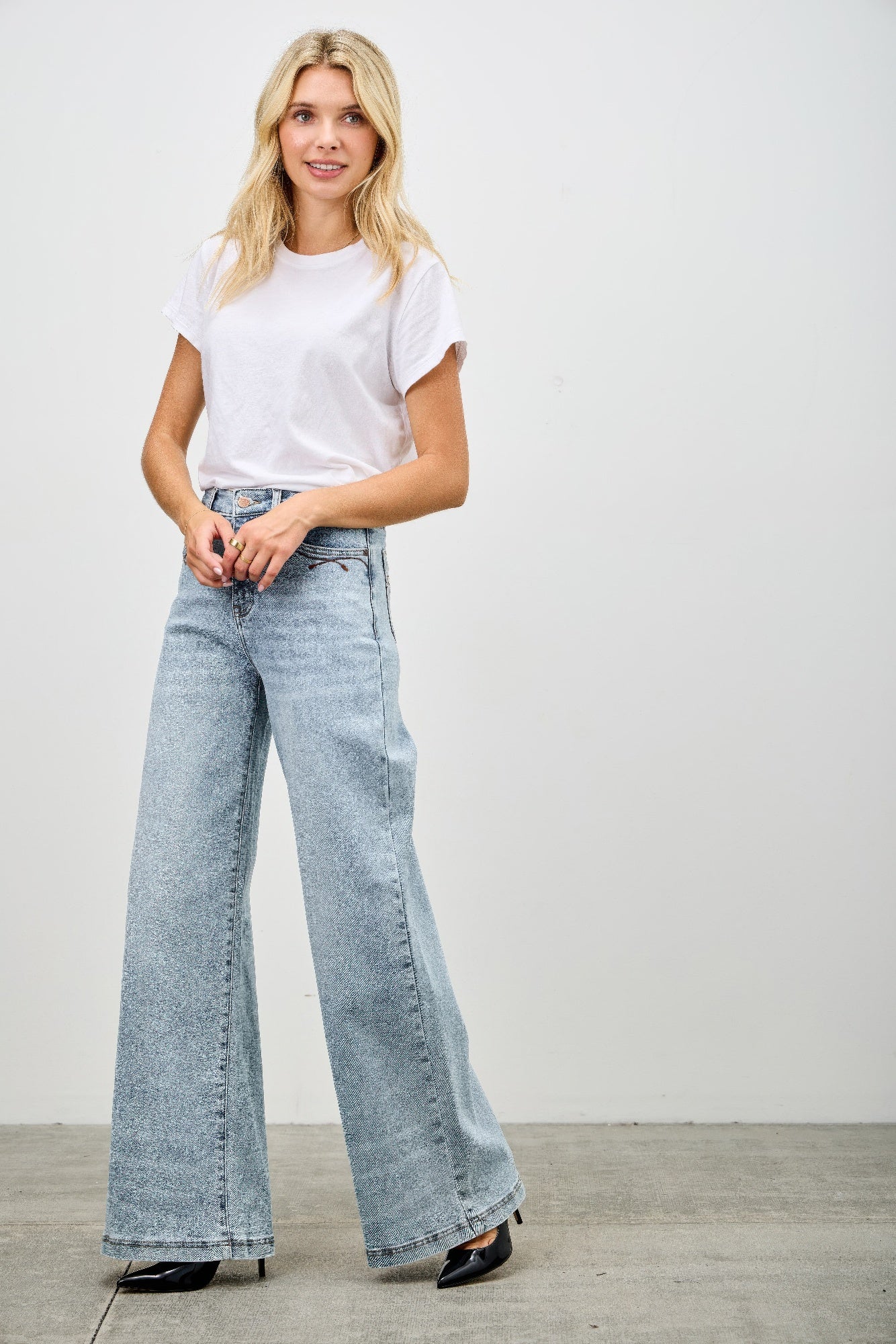 High rise wide-leg jeans on model, light blue denim flare with button closure