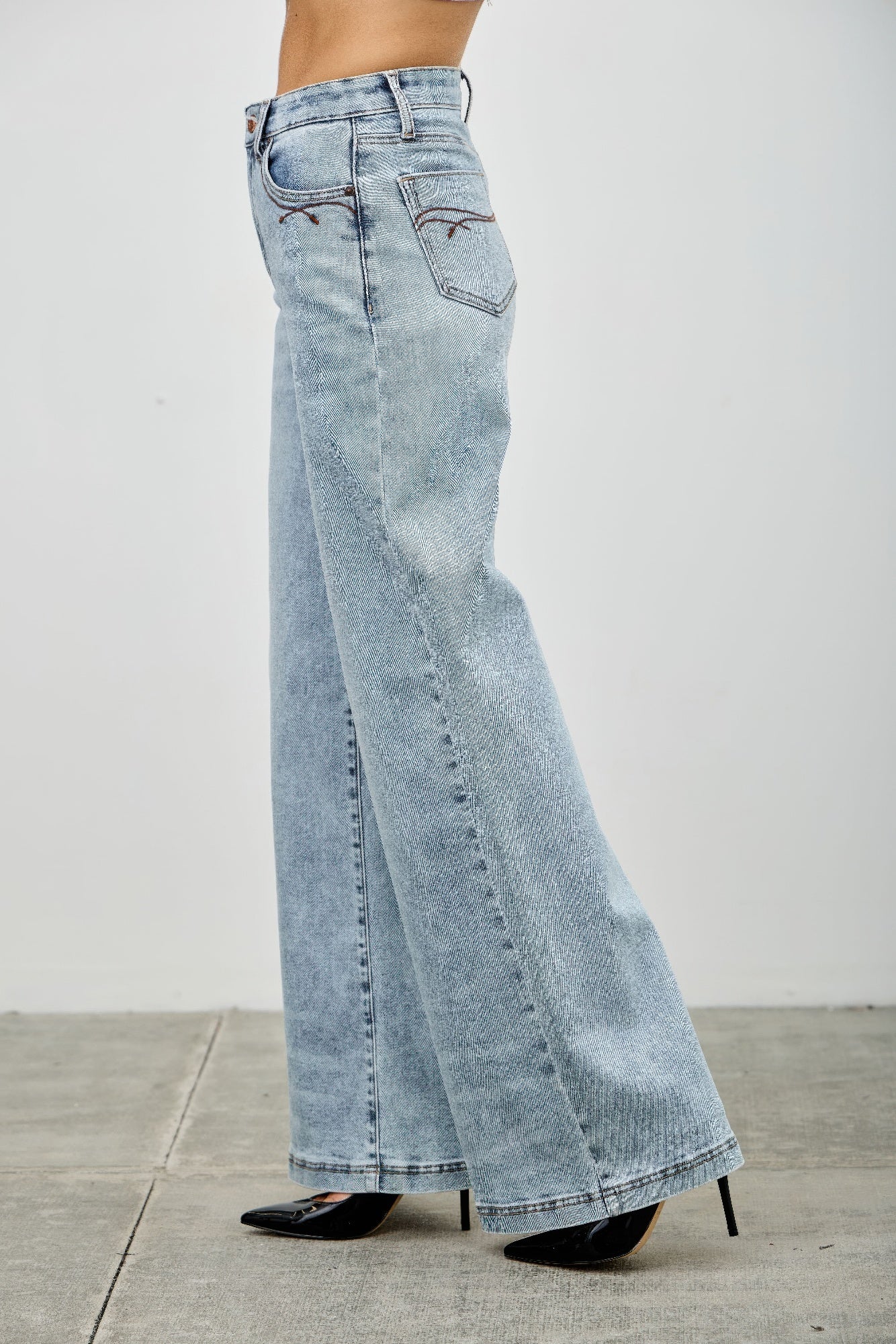 High rise wide-leg jeans side close-up, light blue denim with front patch pocket