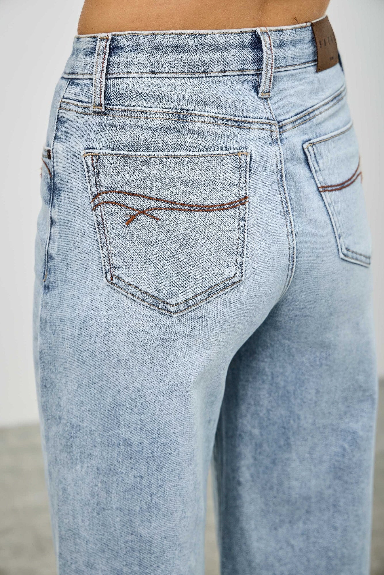 High-rise denim jeans with back yoke and welt pocket, light wash stitching detail
