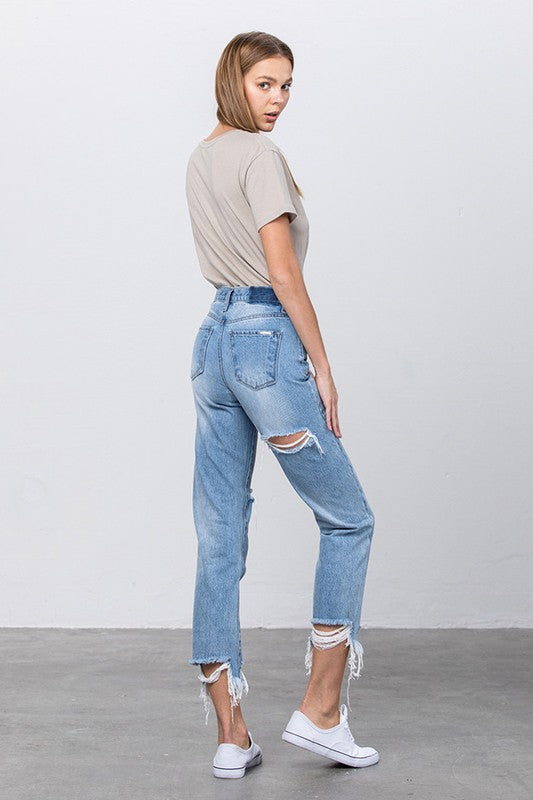 High-waist tapered jeans side view with knee rip and frayed cuffs in medium wash